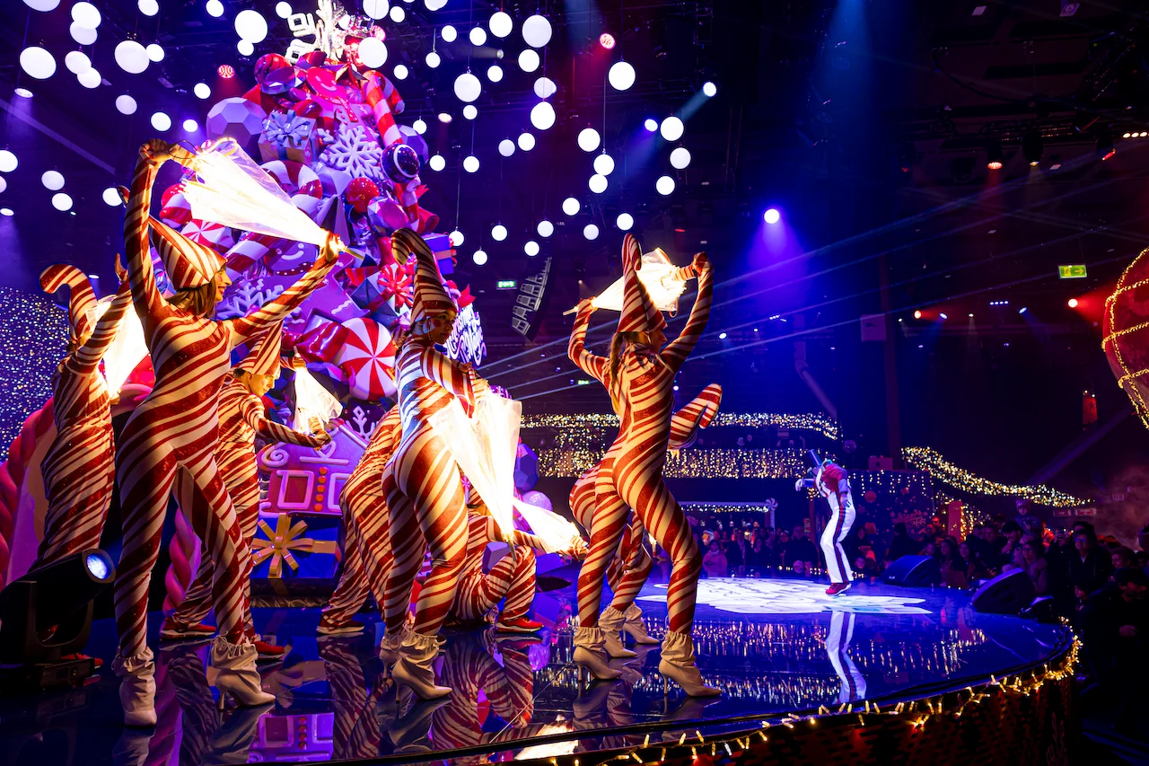 Ballerini in costumi a strisce bianche e rosse da bastoncino di zucchero che si esibiscono su un palco rotondo davanti all'albero – A Christmas Magic all'Allianz MiCo, Milano, Italia, 2023 – progettazione di eventi