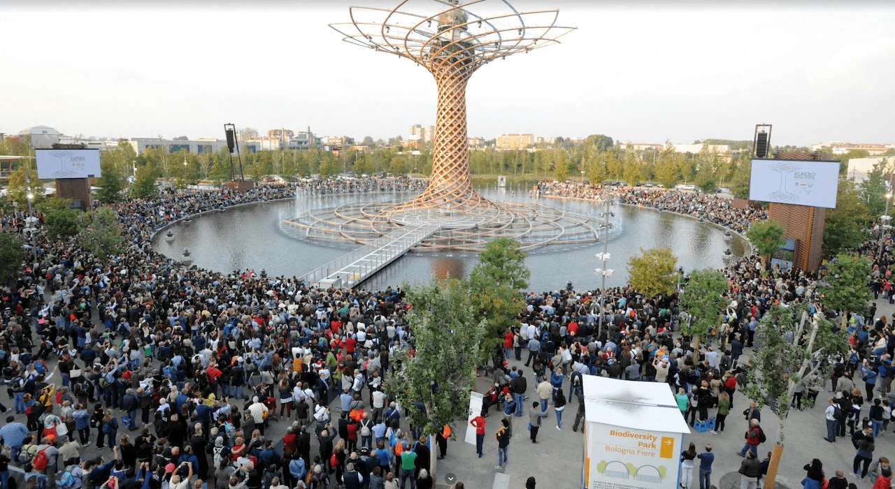 Folla intorno al lago che assiste di giorno allo spettacolo dell'Albero della Vita nel sito di Expo 2015 – Albero della Vita all'Expo 2015, Milano, Italia – progettazione di installazioni
