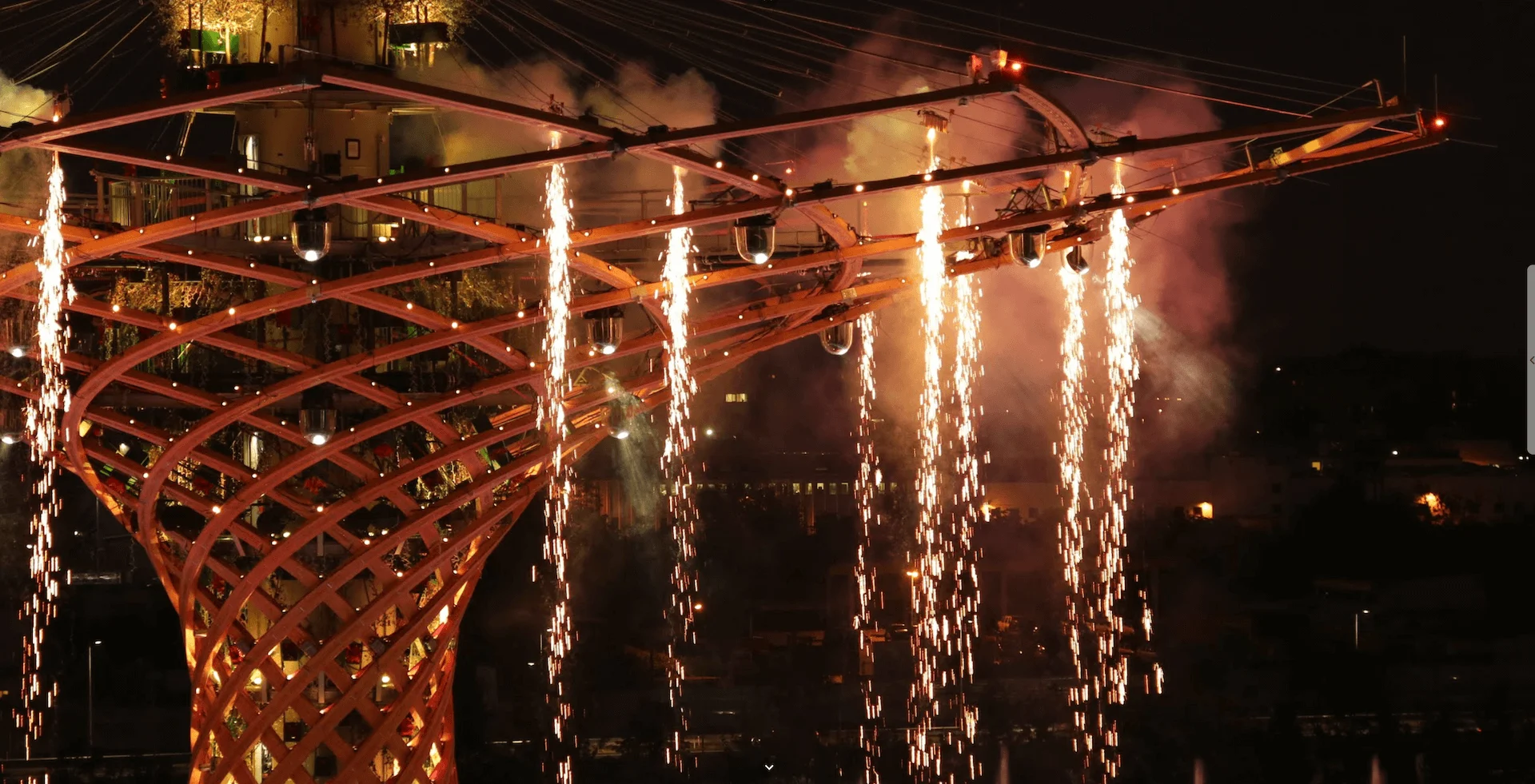Dettaglio del tronco e della chioma a reticolo in legno dell'Albero della Vita con una cascata di fuochi d'artificio di notte – Albero della Vita all'Expo 2015, Milano, Italia – progettazione di installazioni