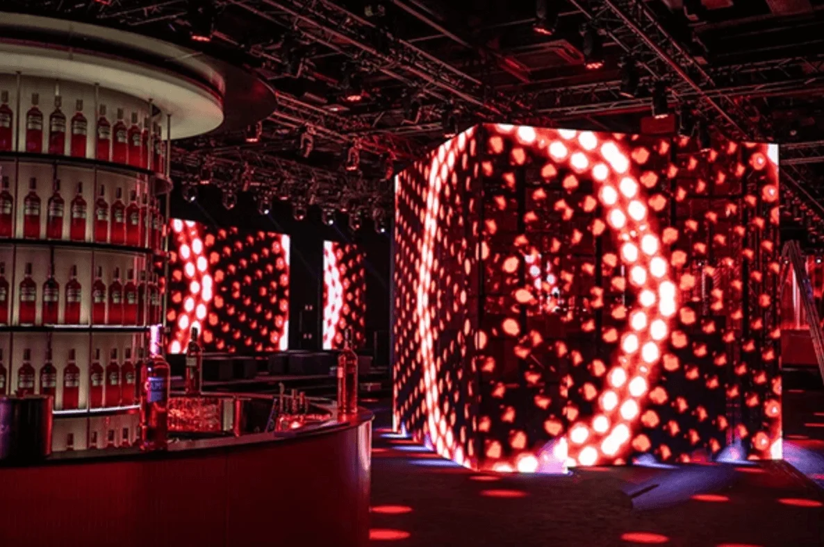 Bar curvo con scaffali di bottiglie Campari accanto a un grande cubo di cerchi LED rossi – Campari Discover Red Party al Festival di Cannes, Francia, 2023 – progettazione di eventi