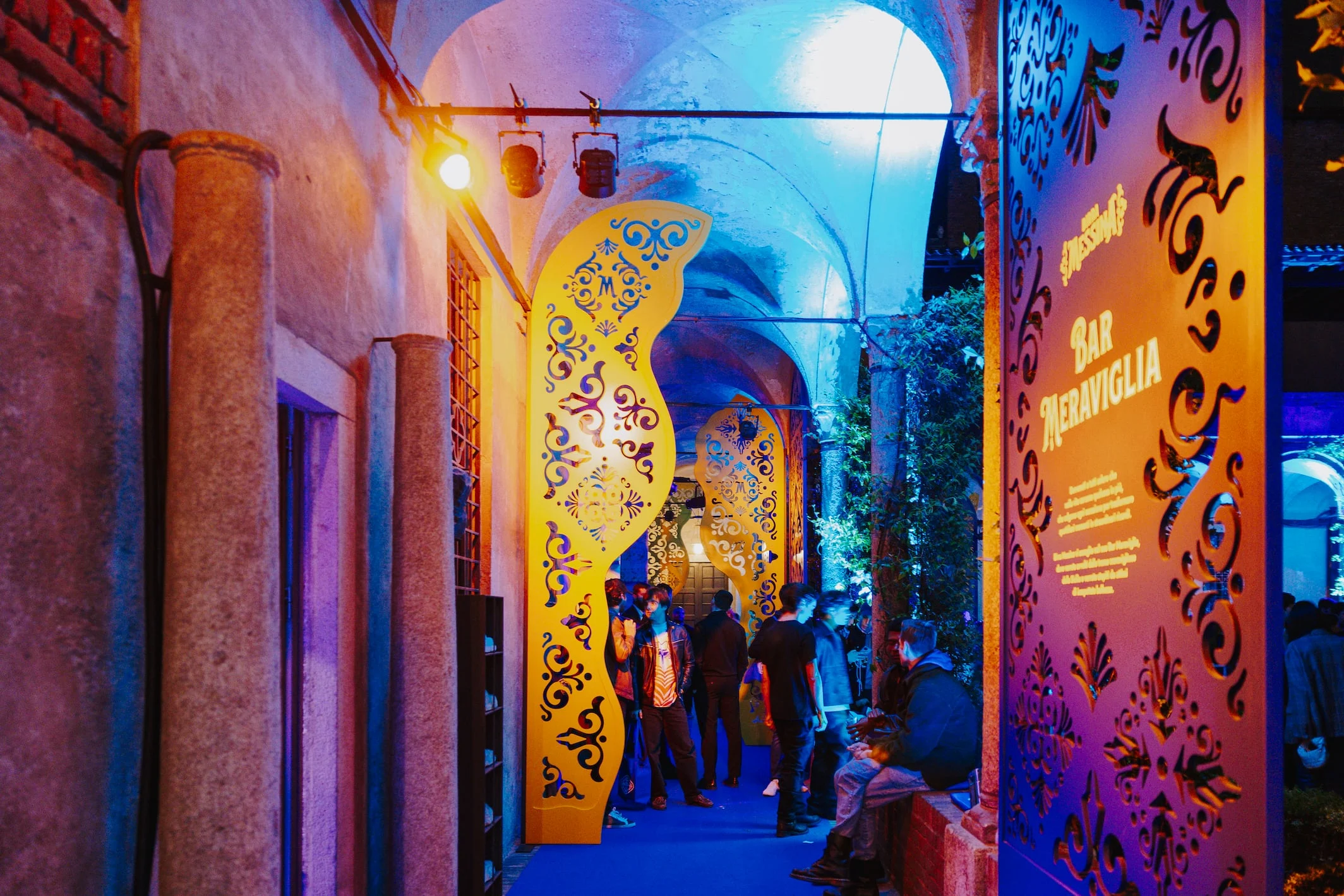 Portico a volte di notte con pannelli traforati dorati, luci colorate e un'insegna Bar Meraviglia – Birra Messina Bar Meraviglia al Fuorisalone, Milano, Italia, 2024 – progettazione di eventi