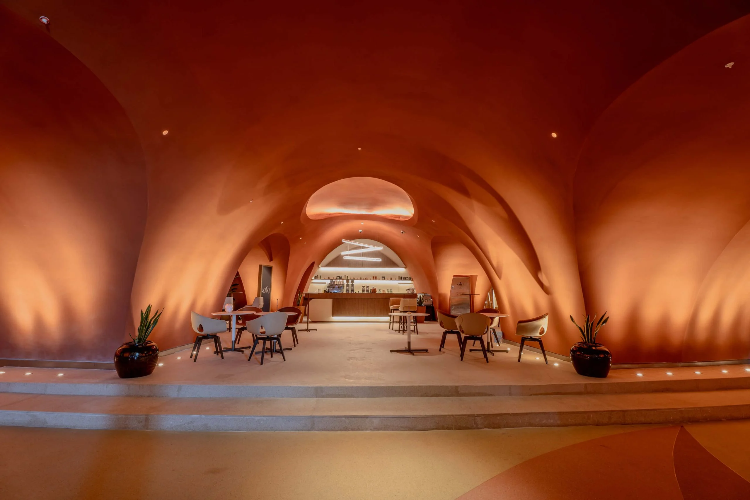 Caffè sotto volte organiche in terracotta, con sedie e tavoli che portano a un bancone retroilluminato – King Fahad Cultural Center, Riyadh, Arabia Saudita, 2024 – riqualificazione architettonica
