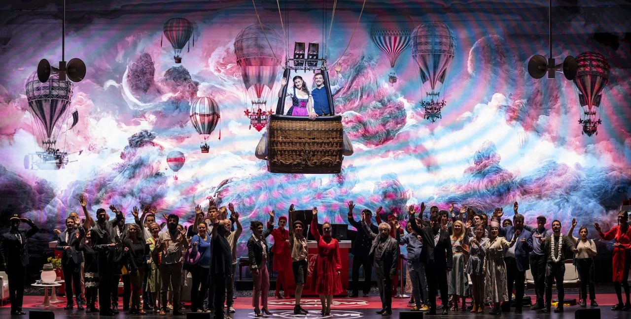 Finale con il cast in festa sotto una mongolfiera e una proiezione di nuvole rosa e azzurre – Une Folle Journée Mozart Gala, Salisburgo, Austria, 2024 – scenografia d'opera
