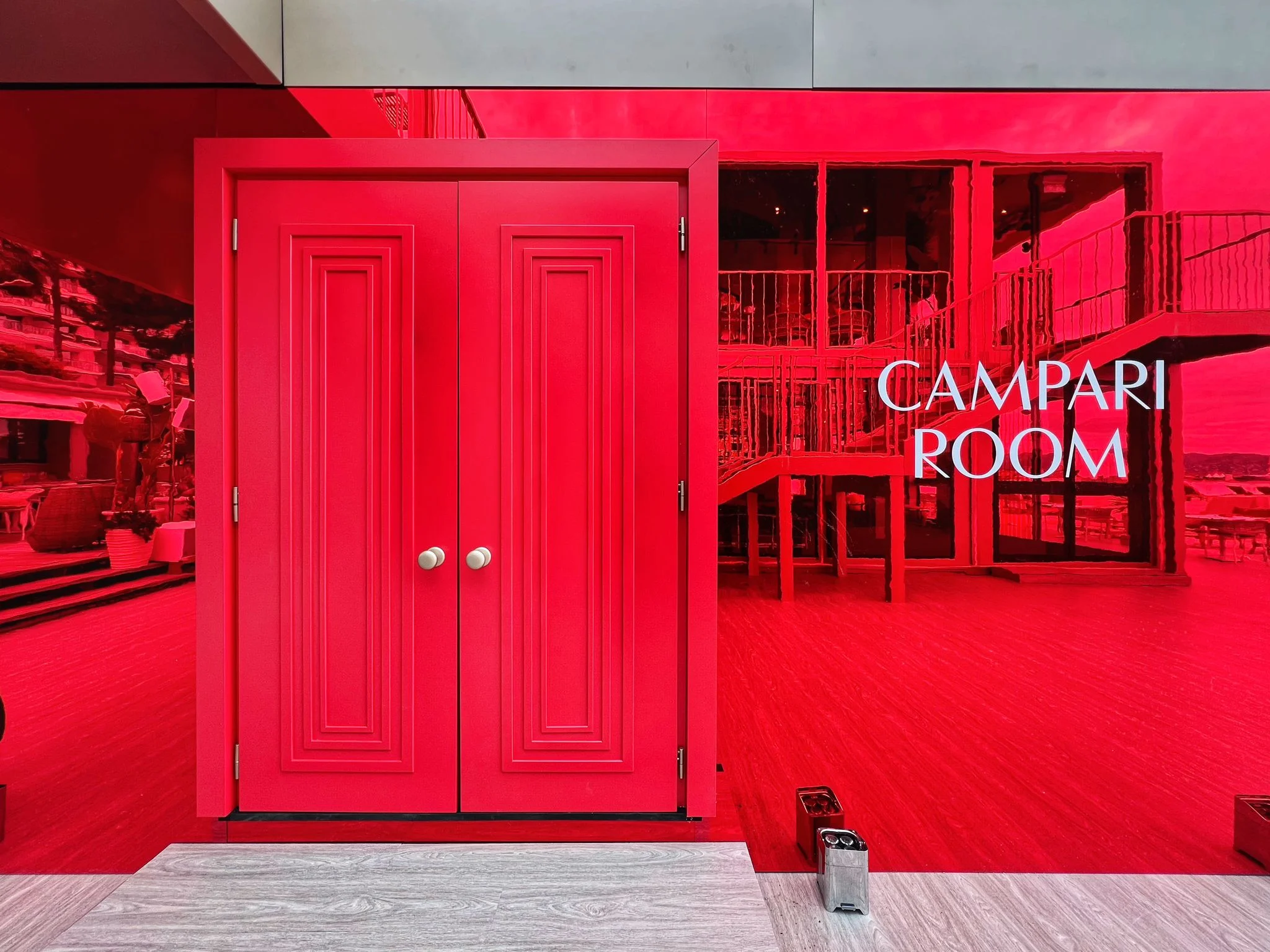 Porta rossa a due battenti in una parete a specchio rossa con la scritta Campari Room – Campari al Festival di Cannes 2024, Francia – architettura per eventi
