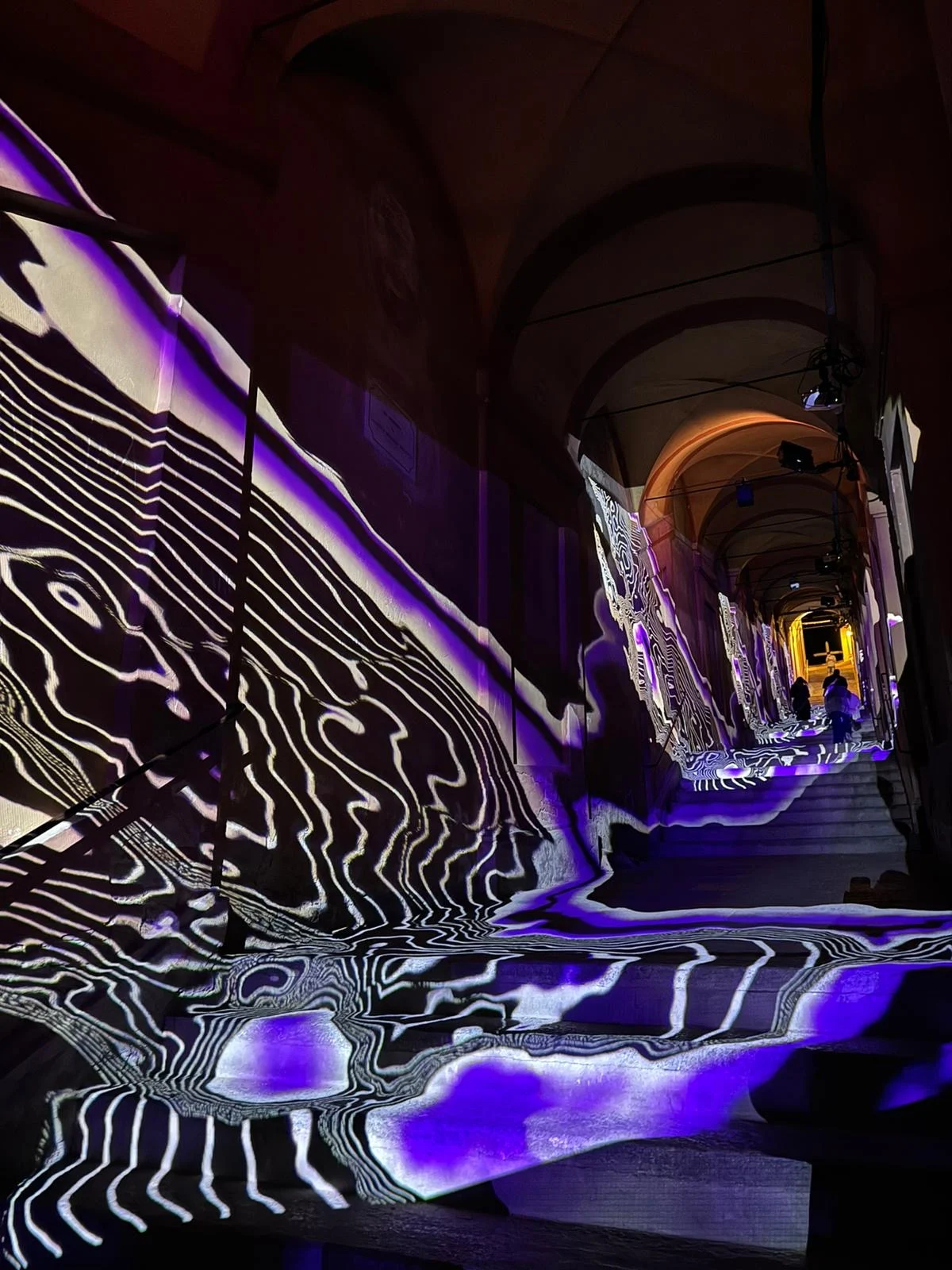 Proiezioni di curve di livello in bianco e nero con macchie viola che scorrono su pareti e scale del portico – Cesare Cremonini Festival dei Portici, Bologna, Italia, 2024 – progettazione di eventi