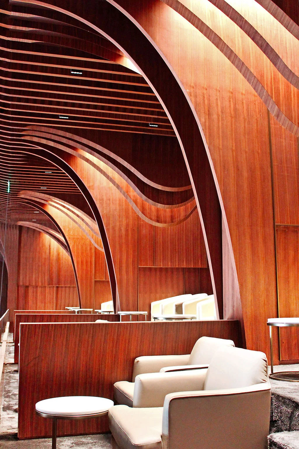 Lounge con nastri di legno curvi che formano archi sopra la testa e poltrone in pelle color crema – Maraya Concert Hall, AlUla, Arabia Saudita, 2019 – architettura