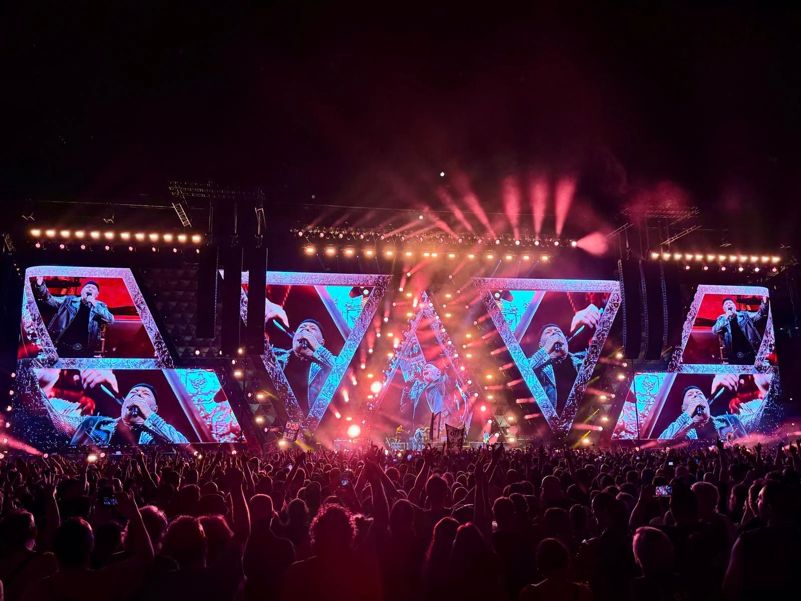 Schermi triangolari in luce rossa e rosa, con fasci di scintille che si aprono a ventaglio sul pubblico – Vasco Rossi Live 2024, Italia – scenografia per concerti