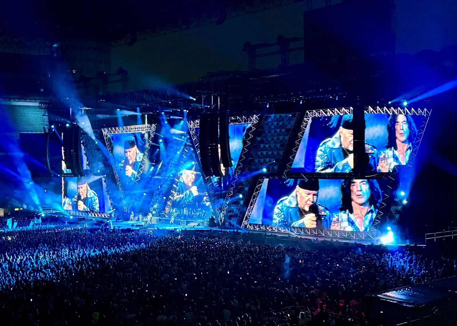 Vista laterale del palco in luce blu, cornici angolari degli schermi con il cantante e un chitarrista – Vasco Rossi Live 2024, Italia – scenografia per concerti