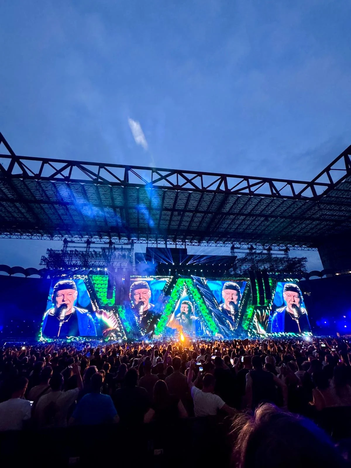 Vista verticale del palco in luce verde sotto la copertura dello stadio e un cielo serale – Vasco Rossi Live 2024, Italia – scenografia per concerti