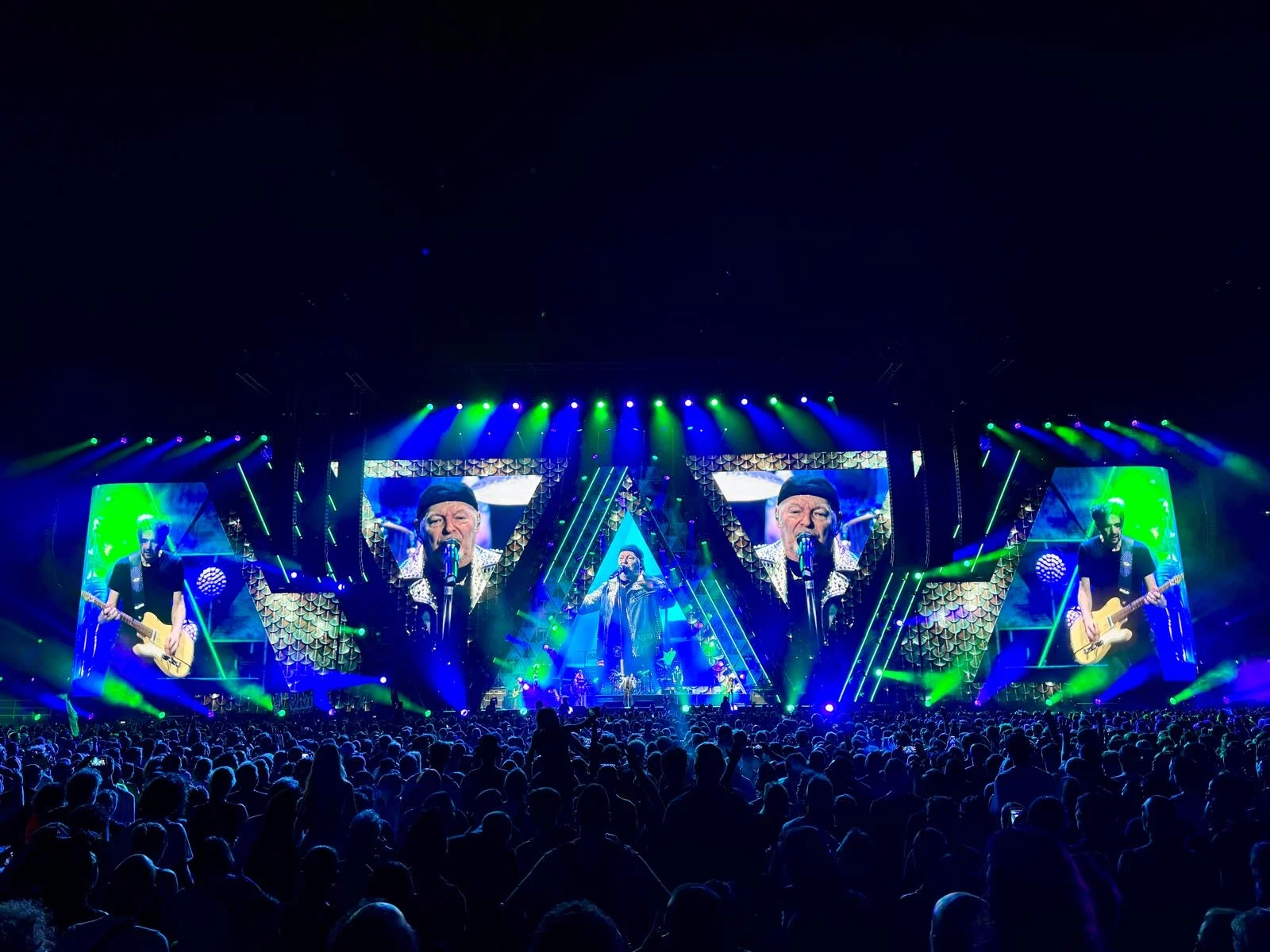 Palco acceso di verde e blu, schermi con il cantante e i chitarristi in cornici angolari – Vasco Rossi Live 2024, Italia – scenografia per concerti