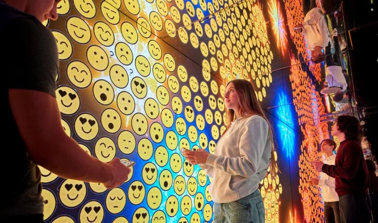Visitatore in una stanza a specchio circondata da pareti di emoji luminose – STEP FuturAbility District by Fastweb, Milano, Italia, 2022 – allestimento espositivo