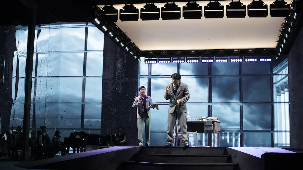 Due artisti sulle scale in una scenografia incorniciata da alte finestre su un cielo in tempesta, con una struttura luci sopra – Waltz Karoly al Turkistan Theatre, Kazakistan, 2024 – scenografia