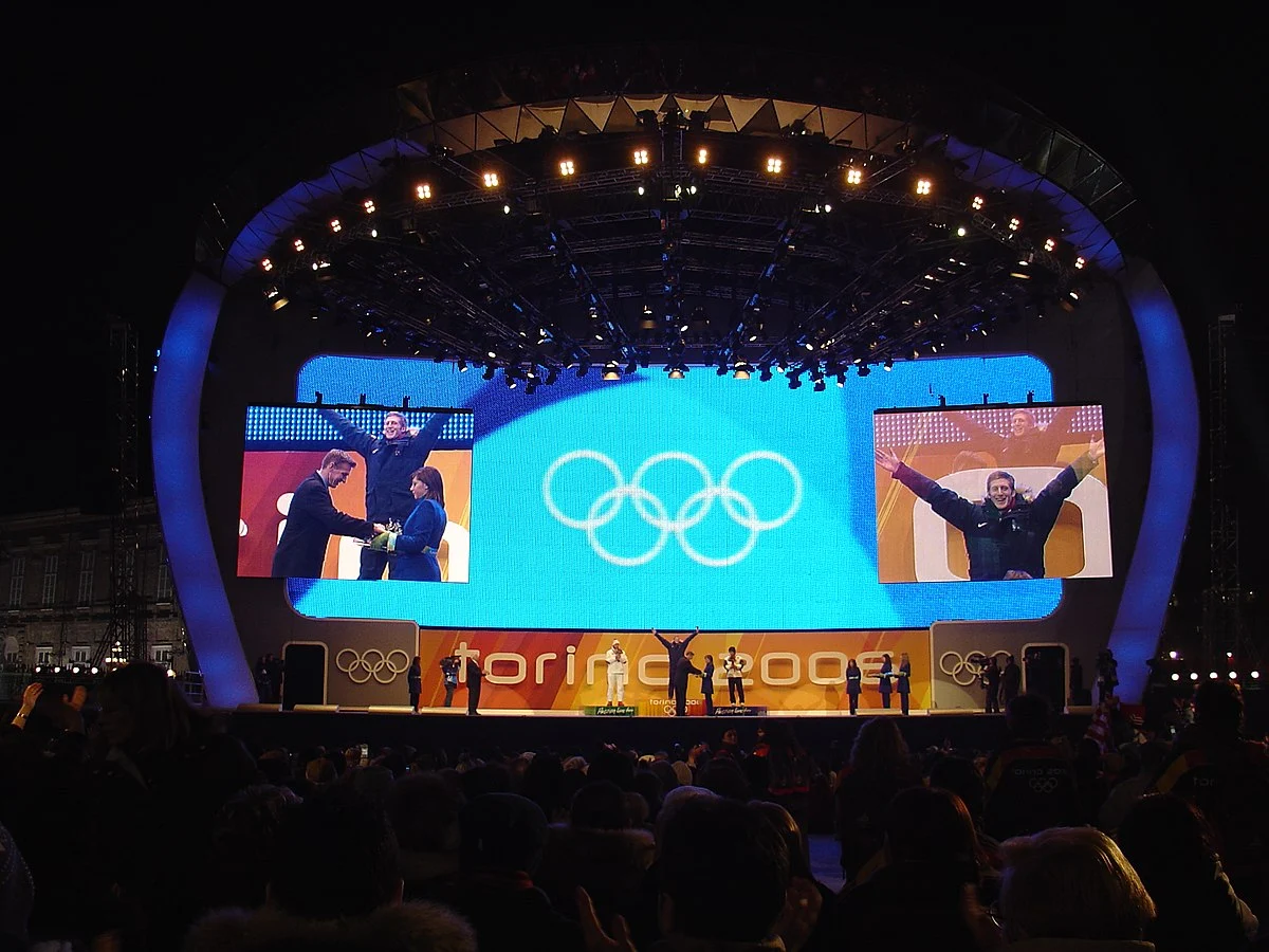 Premiazione sul palco curvo, cerchi olimpici sullo schermo centrale e Torino 2006 sul fronte – Medals Plaza, Olimpiadi invernali di Torino 2006, Italia – progettazione di eventi