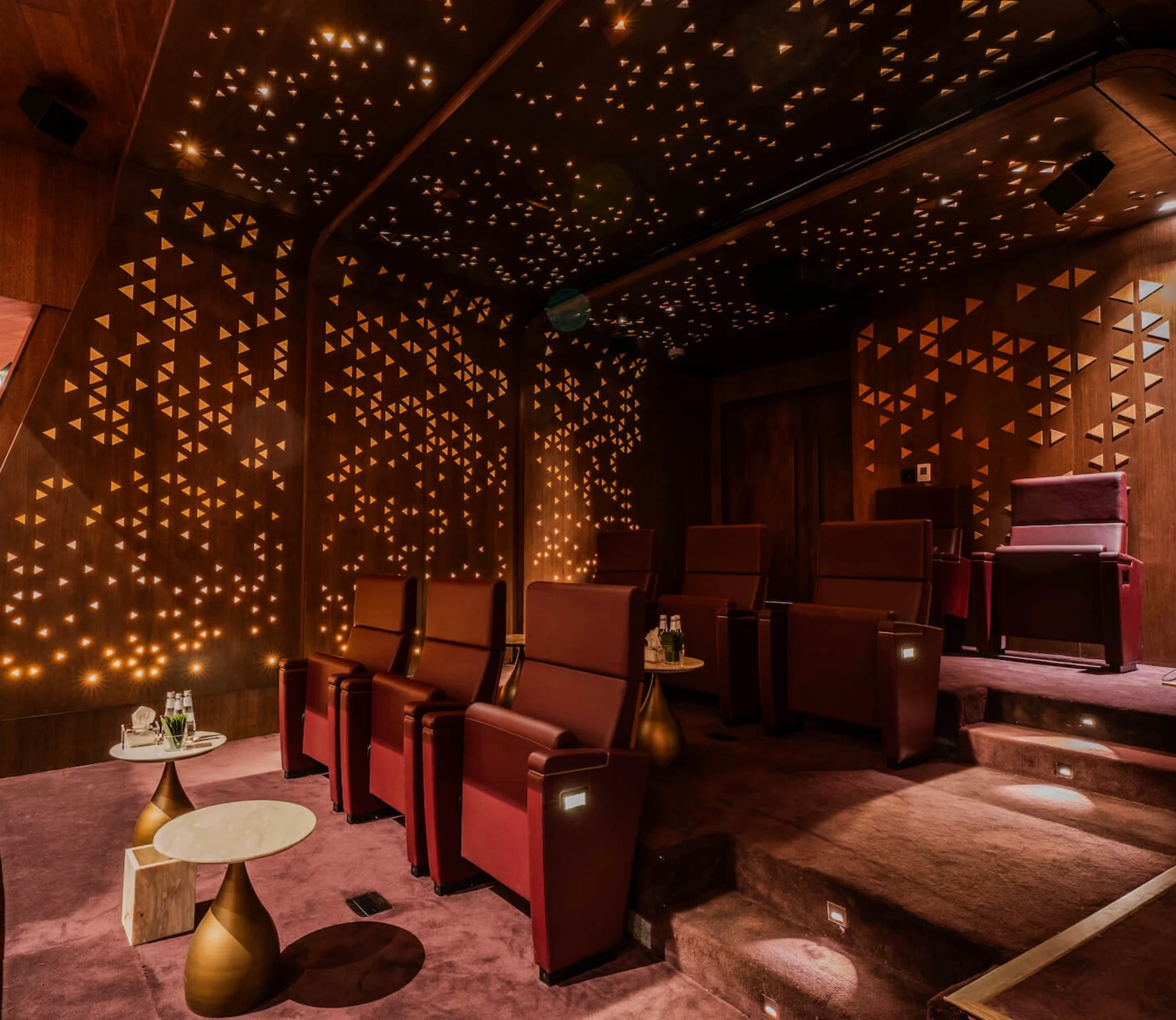 Palco del teatro con poltrone rosse King Fahad e tavolini in ottone, pareti forate da luci triangolari – King Fahad Chair per Poltrona Frau, Riyadh, Arabia Saudita, 2024 – design di prodotto