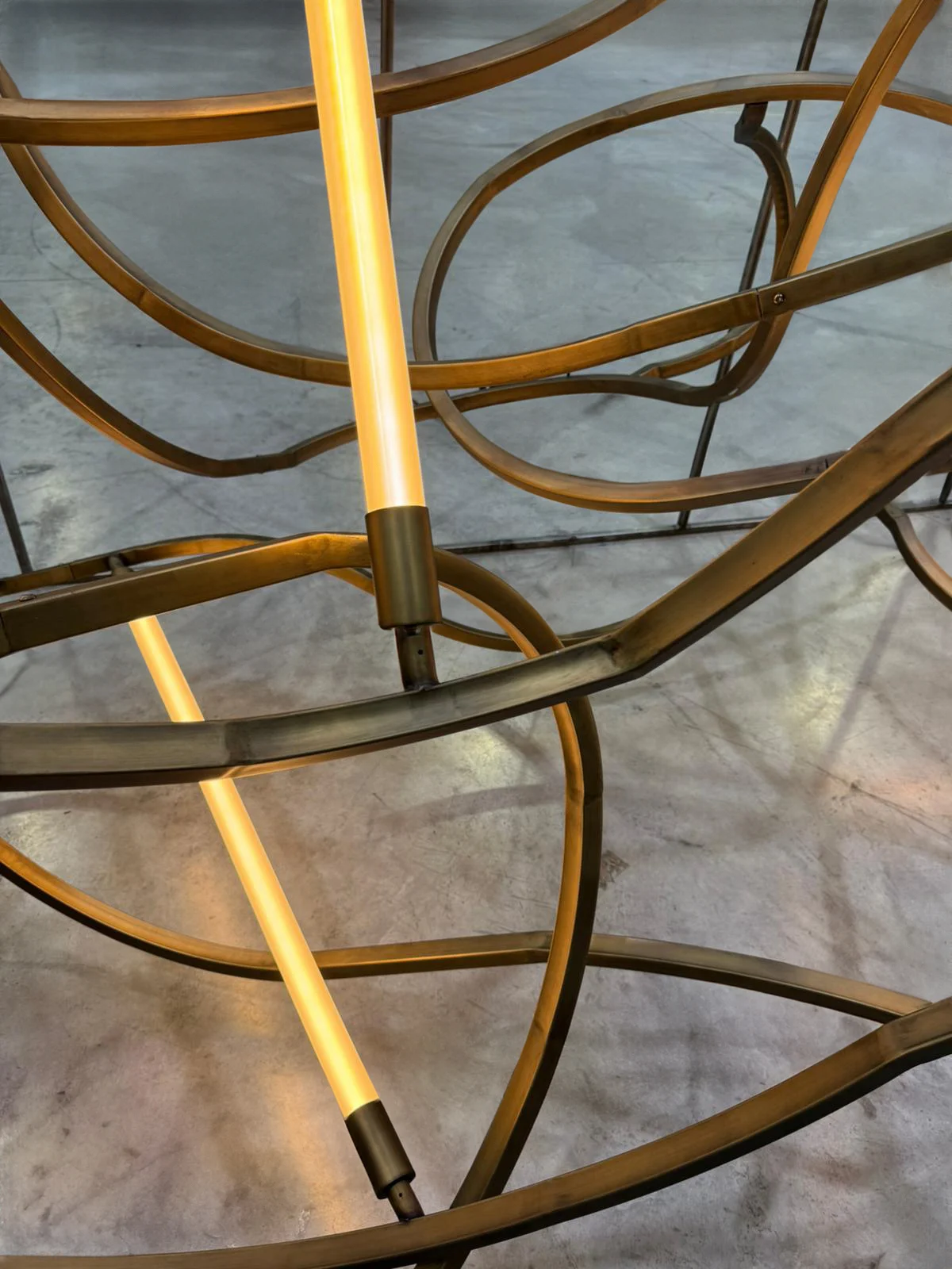 Dettaglio delle sezioni curve di binario e di un tubo luminoso acceso con raccordi in ottone – Lampadario The Chedi Hegra, AlUla, Arabia Saudita, 2025 – lighting design
