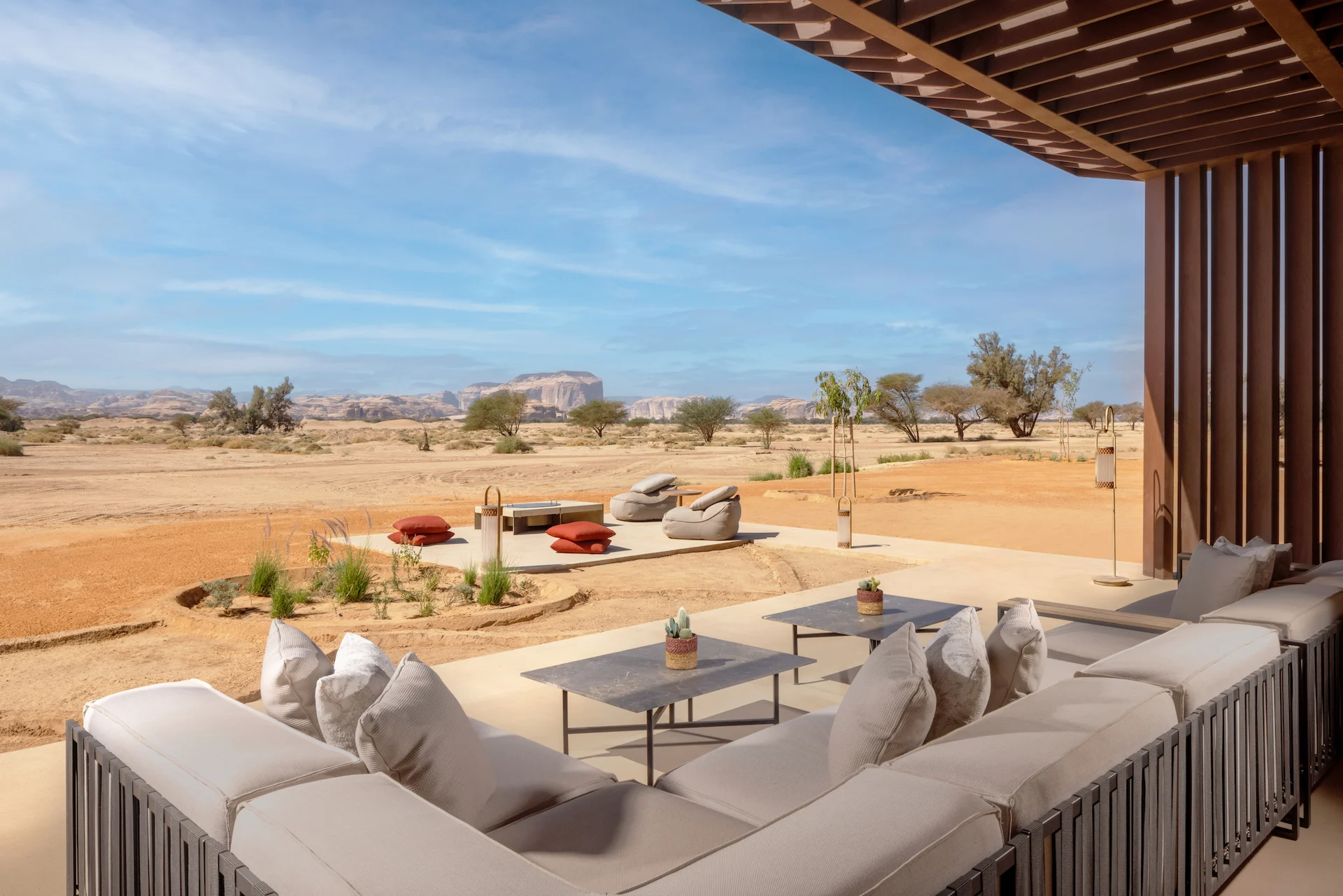 Terrazza ombreggiata con divano e tavolini bassi affacciata sul deserto e su una lounge con braciere – The Chedi Hegra, AlUla, Arabia Saudita, 2024 – architettura alberghiera