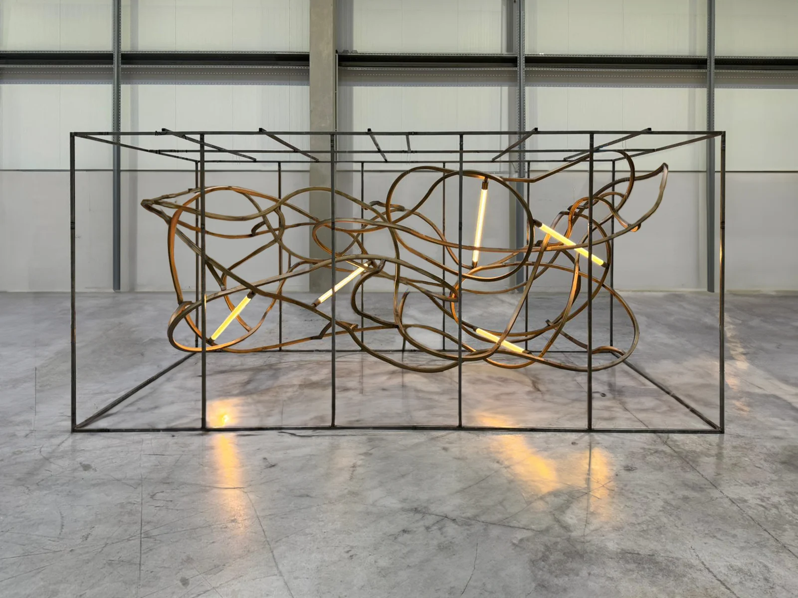 Lampadario di vecchi binari ferroviari piegati e intrecciati in un telaio d'acciaio, con tubi luminosi, in un laboratorio – Lampadario The Chedi Hegra, AlUla, Arabia Saudita, 2025 – lighting design