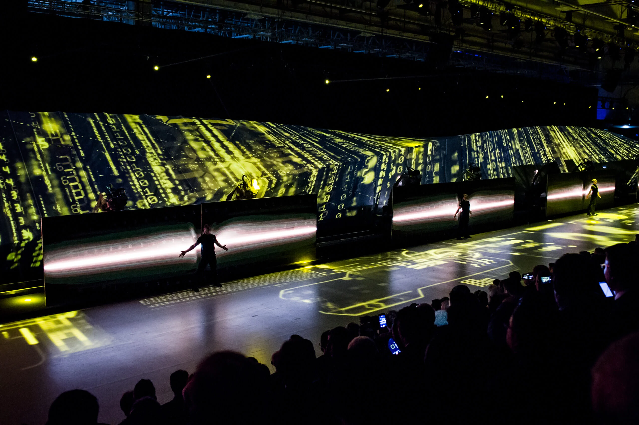 Artisti sul lungo palco davanti a schermi con proiezioni di dati verdi, pubblico che filma con il telefono – Anteprima mondiale Lamborghini Urus, Sant'Agata Bolognese, Italia, 2017 – progettazione di eventi