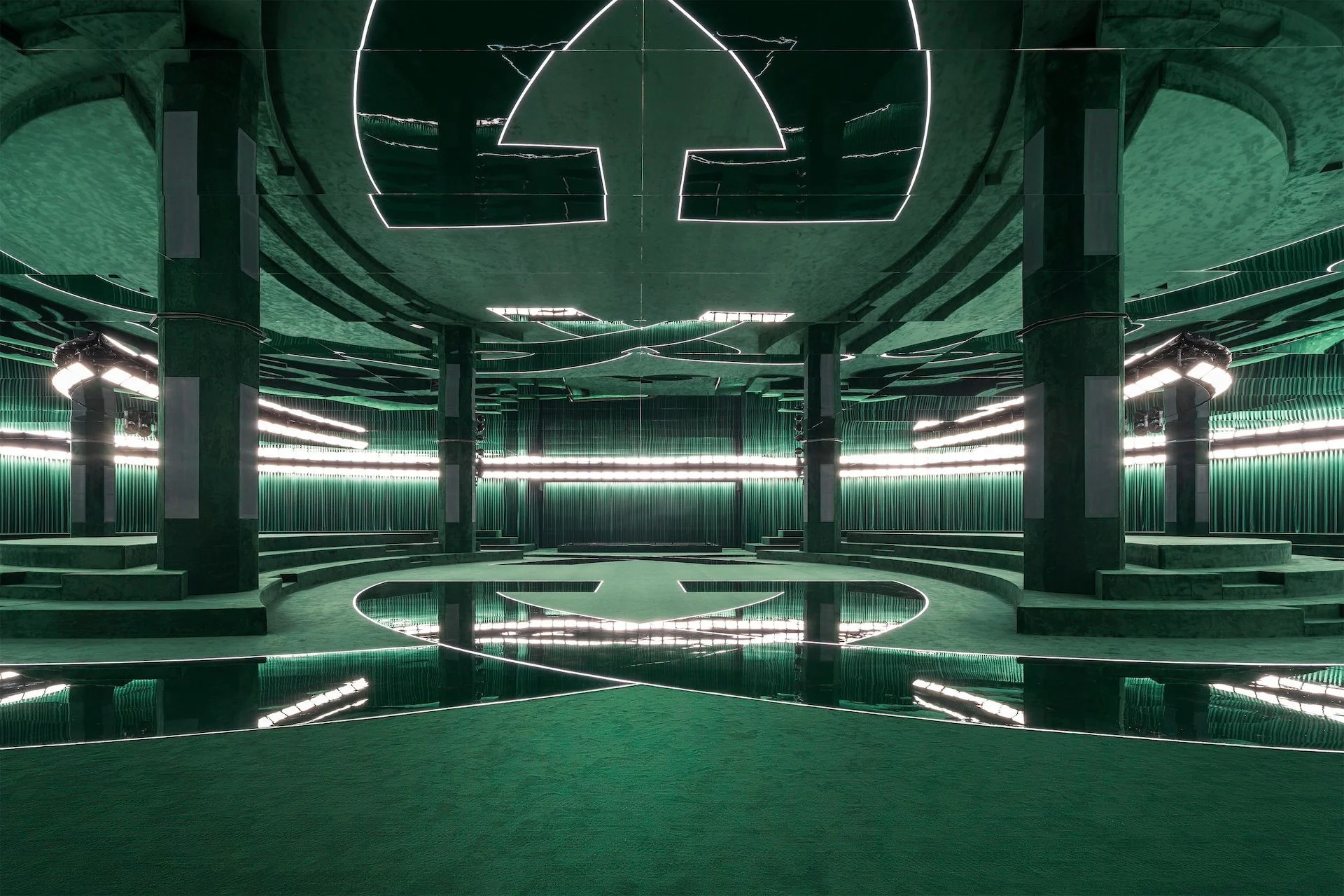 Lo spazio della sfilata Gucci A/I 2025: anfiteatro in velluto verde, pavimento a specchio e la Interlocking G disegnata con la luce – Gucci Autunno/Inverno 2025, Milano, Italia – scenografia per sfilate