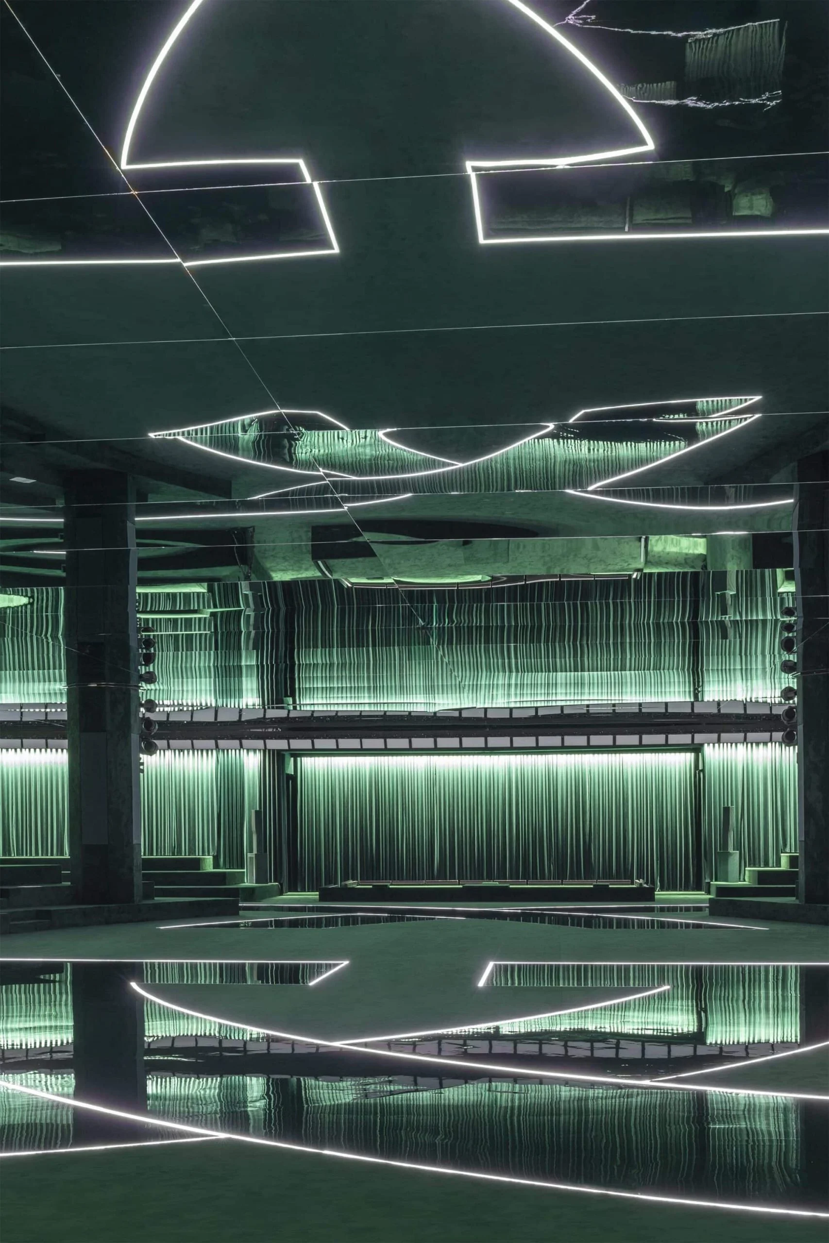 Vista verticale della location verde della sfilata: archi al neon sul soffitto a specchio riflessi nel pavimento lucido – Gucci Autunno/Inverno 2025, Milano, Italia – scenografia per sfilate