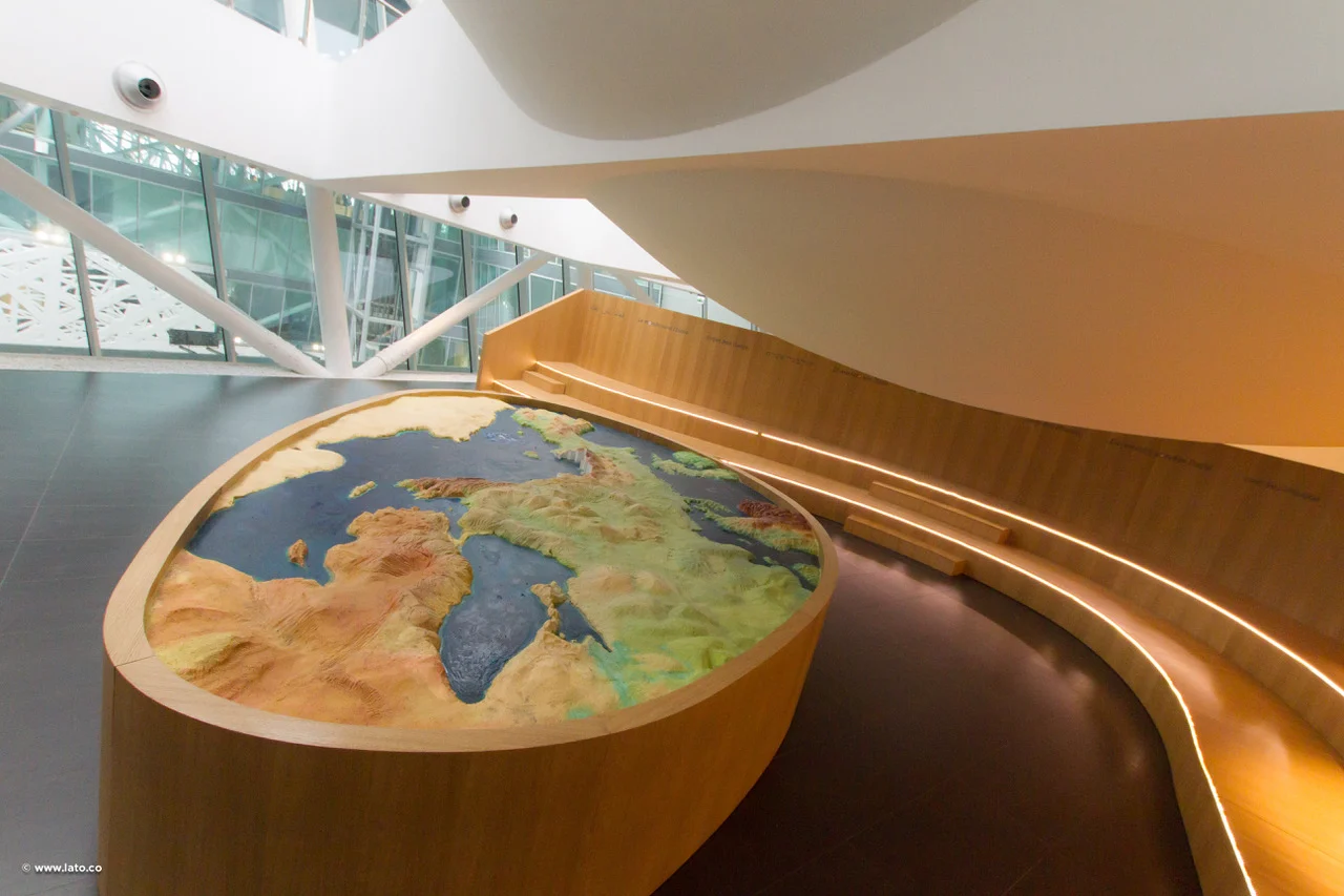 Plastico in rilievo dell'Italia e del Mediterraneo su una base ovale in legno, con una panca curva in legno – Padiglione Italia all'Expo 2015, Milano, Italia – allestimento espositivo