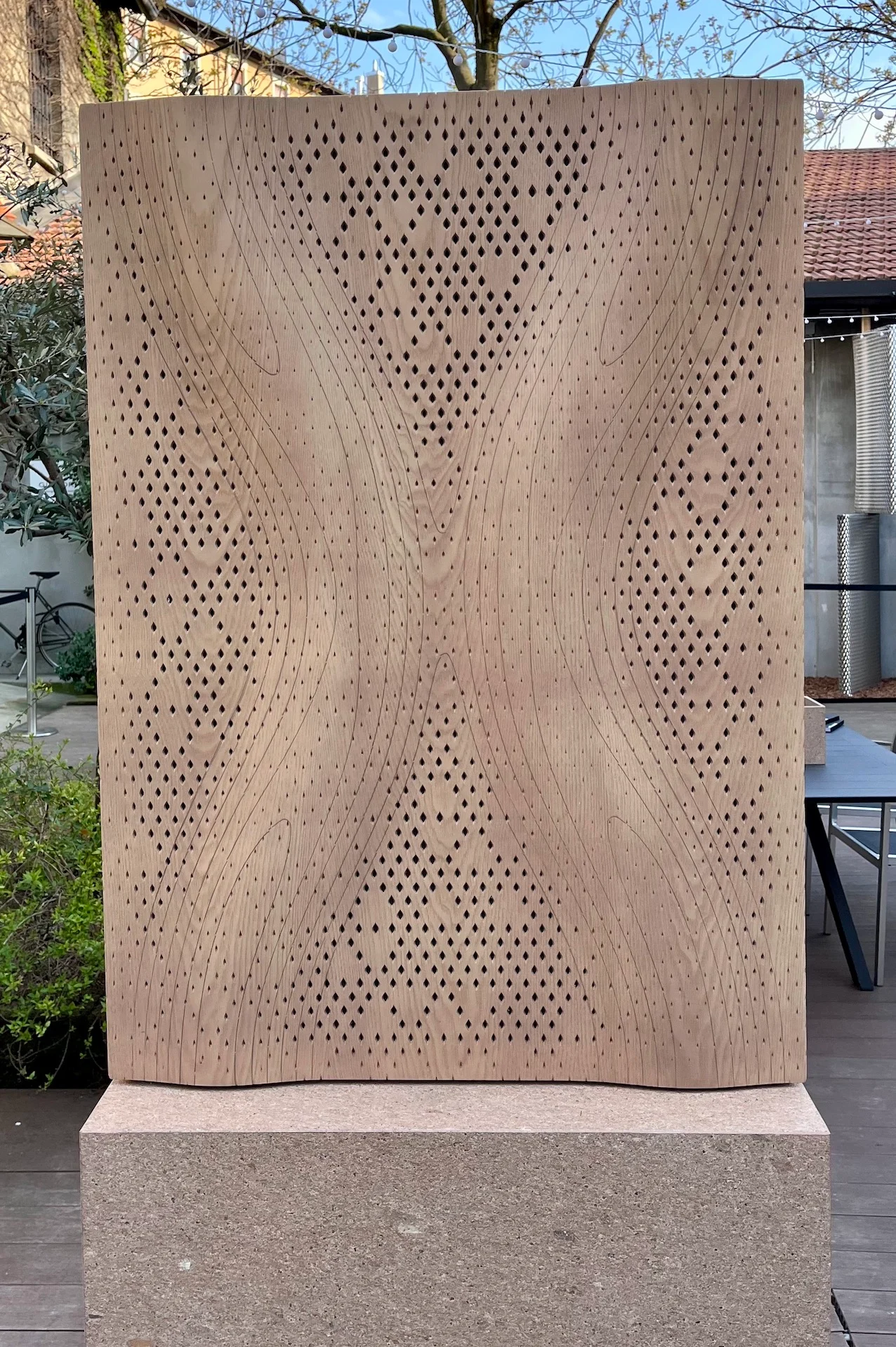 Pannello acustico in legno con motivo a rombi traforato e superficie ondulata su una base di pietra all'aperto – Pannelli Woodflow-Skin Strong by Form, Milano, Italia, 2025 – design di prodotto