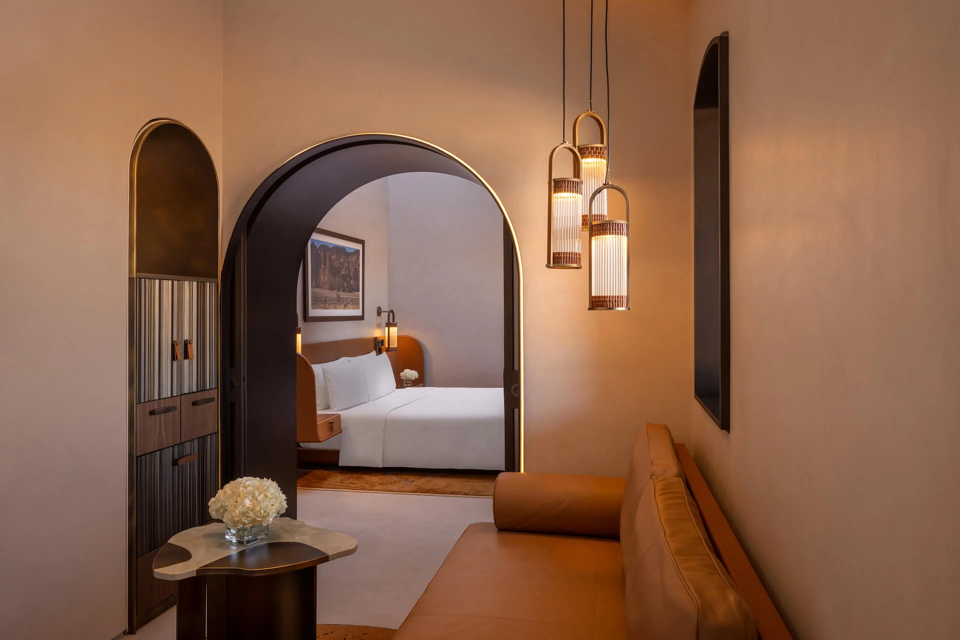 Suite d'hotel con tre lanterne appese accanto a una porta ad arco che conduce alla camera da letto – Lanterna AlUla per Artemide, Milano, Italia, 2025 – lighting design