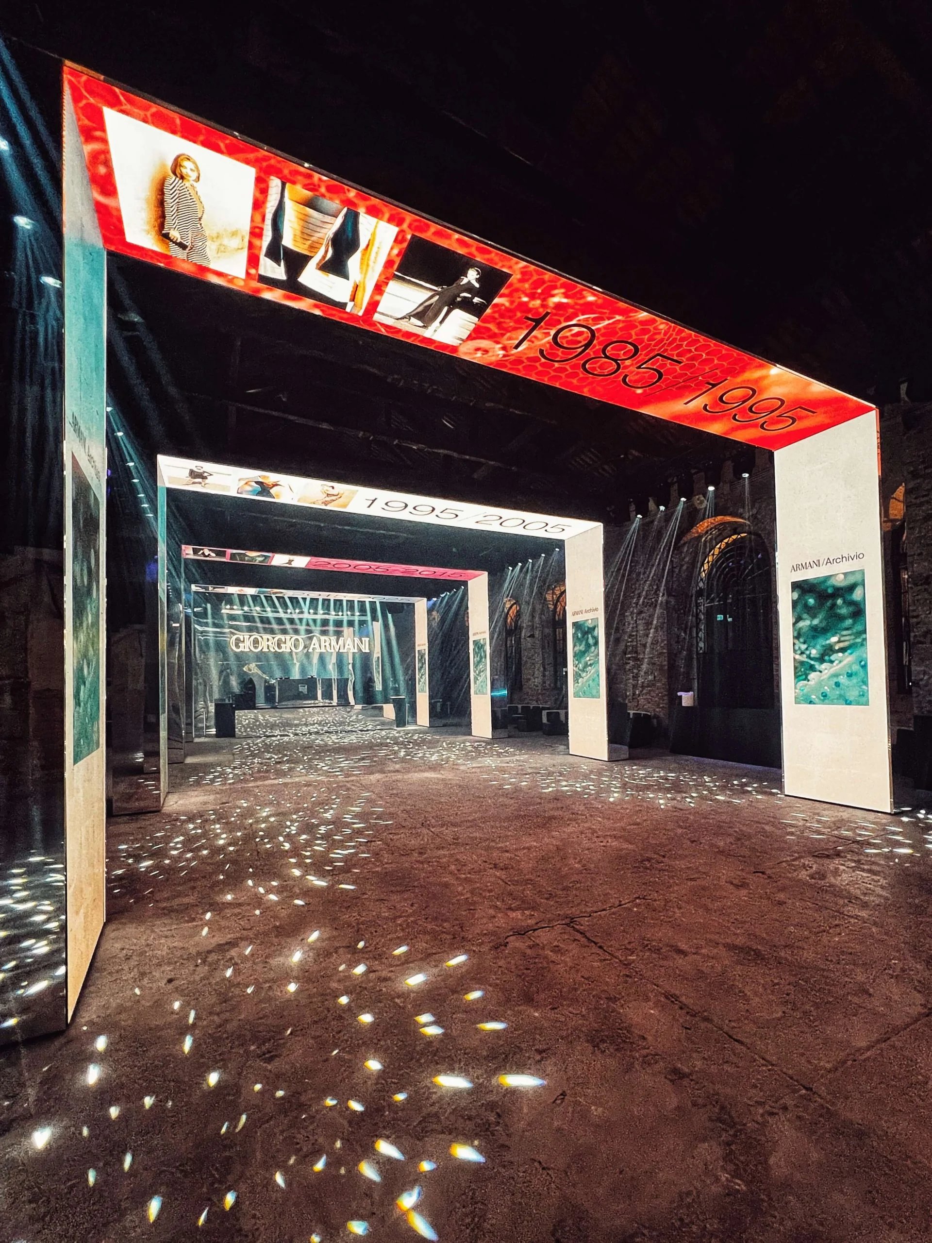 Portale rosso 1985/1995 che conduce ad altri portali dei decenni, con punti di luce scintillanti sul pavimento – Festa Armani/Archivio alla Mostra del Cinema di Venezia, Italia, 2025 – progettazione di eventi