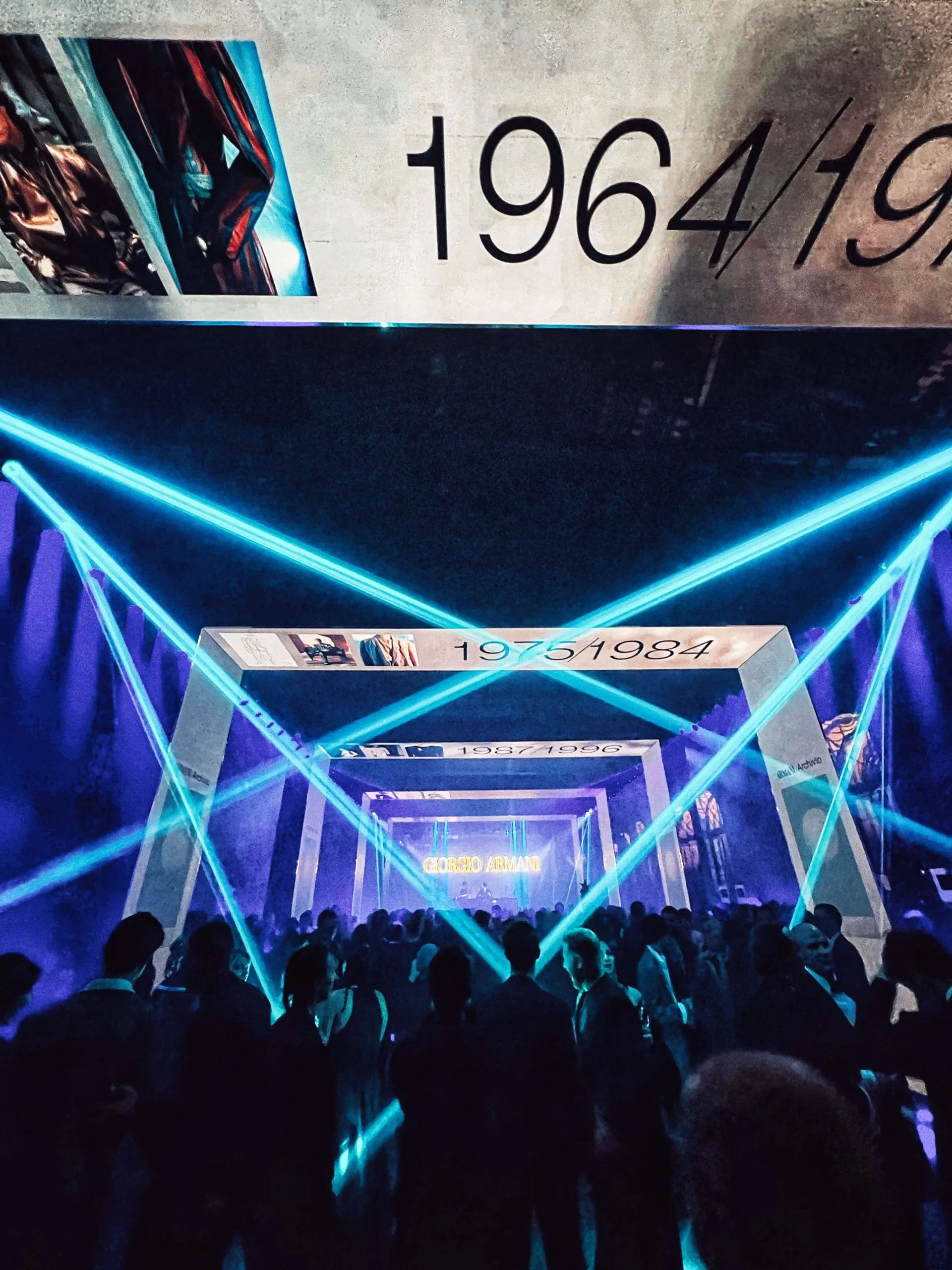 Ospiti alla festa sotto fasci laser turchesi incrociati, sullo sfondo il corridoio dei portali dei decenni – Festa Armani/Archivio alla Mostra del Cinema di Venezia, Italia, 2025 – progettazione di eventi