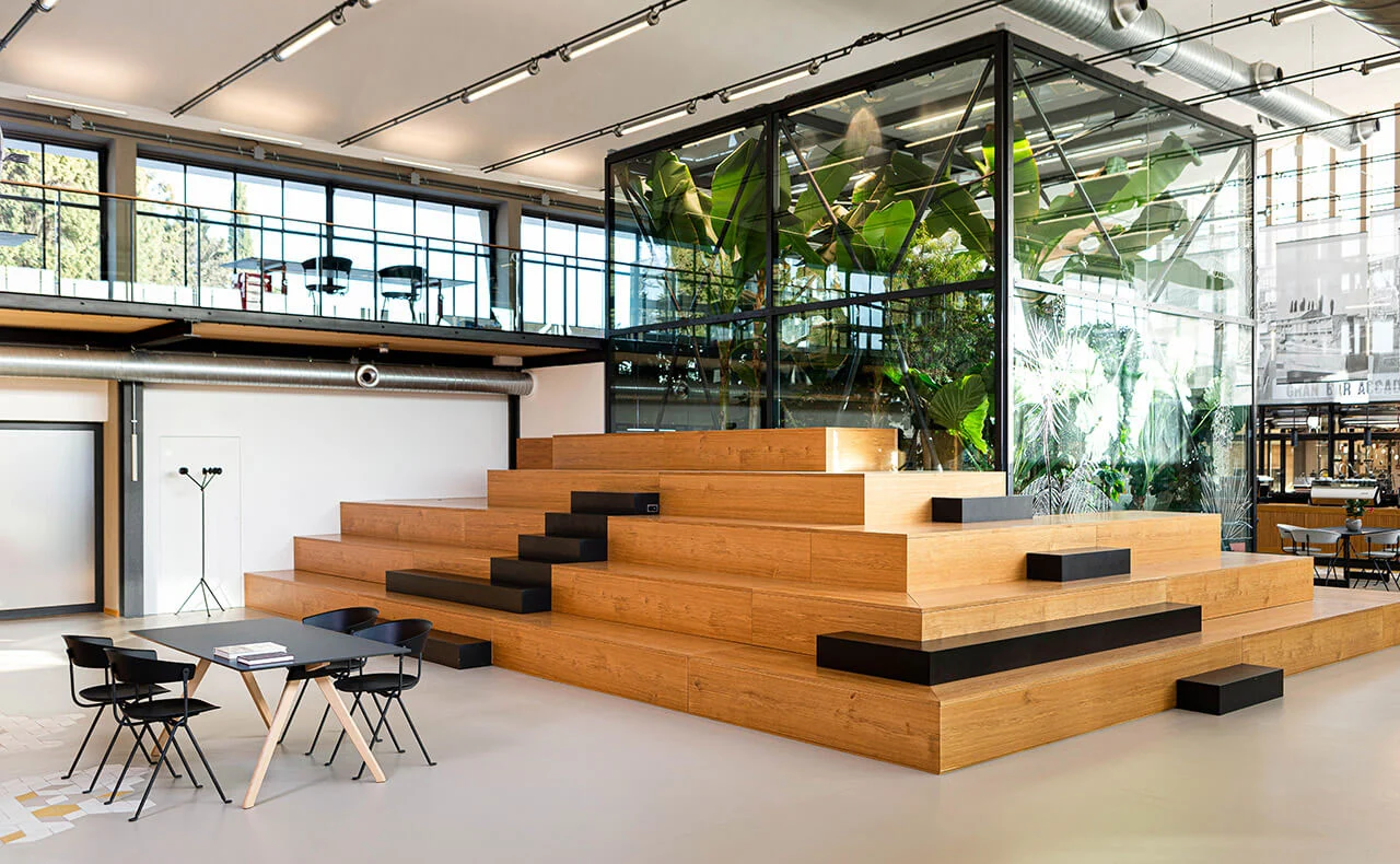 Grande gradonata in rovere con cuscini neri davanti alla serra di vetro e a un soppalco – La Marzocco Accademia del Caffè Espresso, Firenze, Italia, 2018 – interior design
