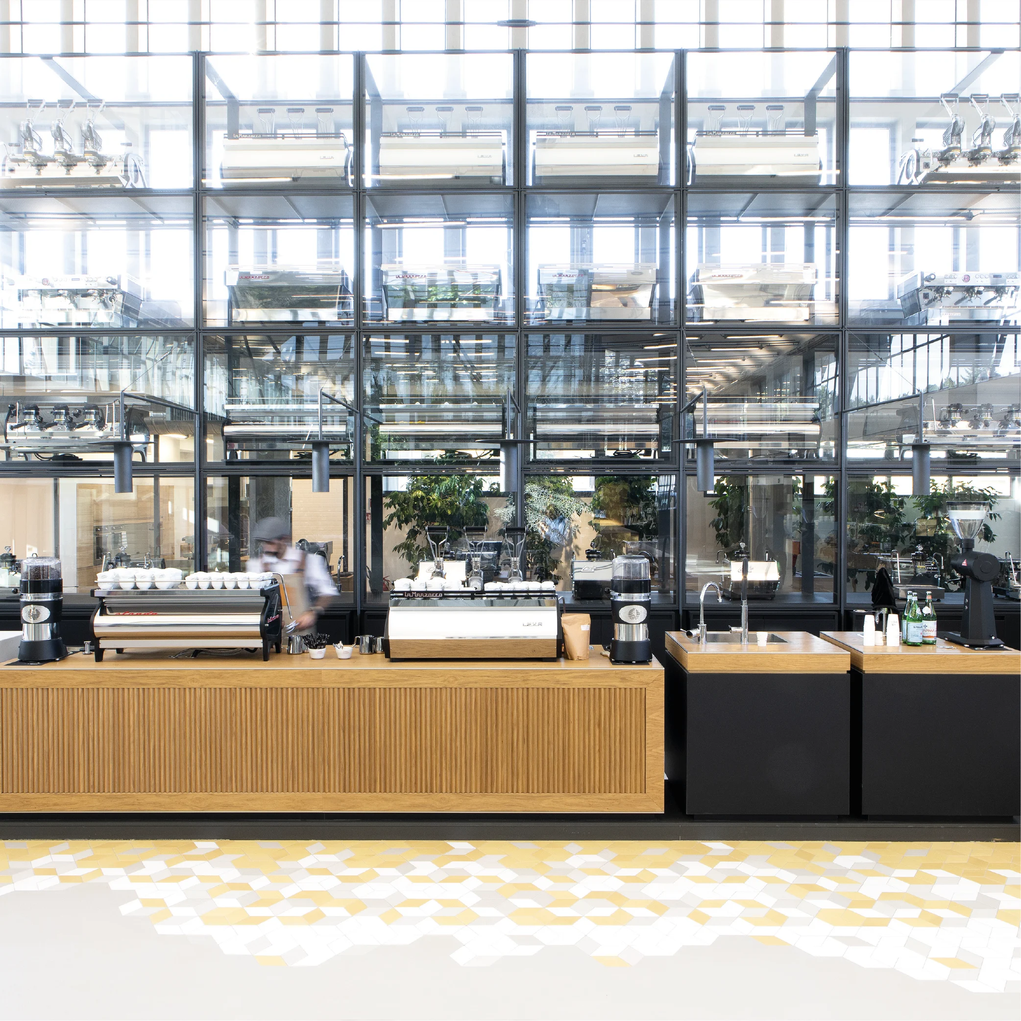 Caffetteria con bancone a listelli di rovere e macchine per espresso davanti a un'alta vetrata con macchine esposte – La Marzocco Accademia del Caffè Espresso, Firenze, Italia, 2018 – interior design