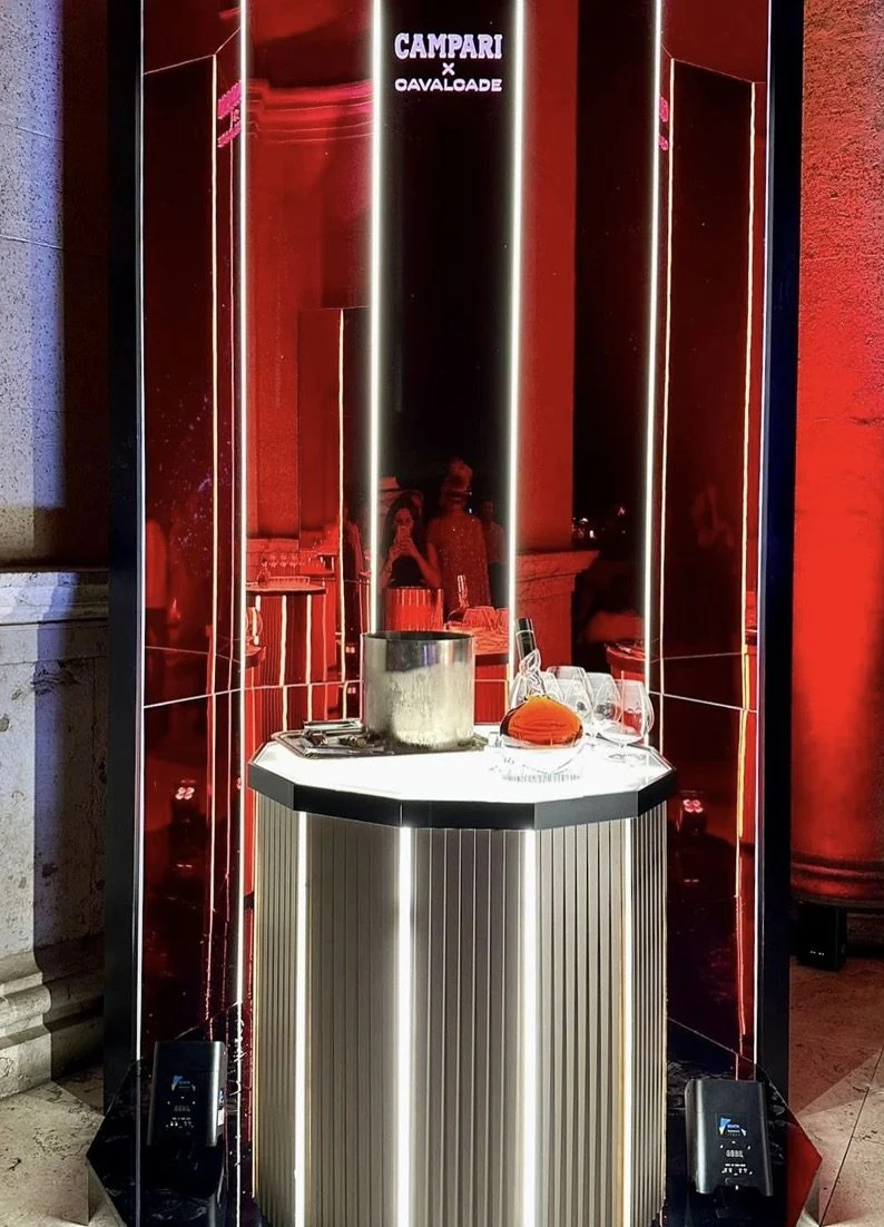 Chiosco ottagonale a specchio con il piano illuminato che regge un secchiello del ghiaccio e bicchieri – Campari Cavalcade, Roma, Italia, 2023 – progettazione di eventi