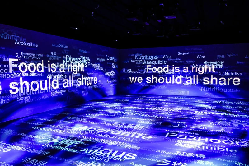 Sala buia con la scritta Food is a right we should all share e parole in molte lingue proiettate su pareti e pavimento – FAO MuNe Museo dell'alimentazione e dell'agricoltura, Roma, Italia, 2025 – allestimento espositivo