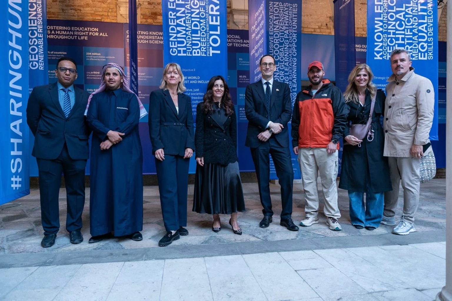 Gruppo di ospiti in posa davanti agli stendardi blu della mostra nel cortile di Palazzo Zorzi – Deep Surfaces a Palazzo Zorzi, Venezia, Italia, 2025 – allestimento espositivo