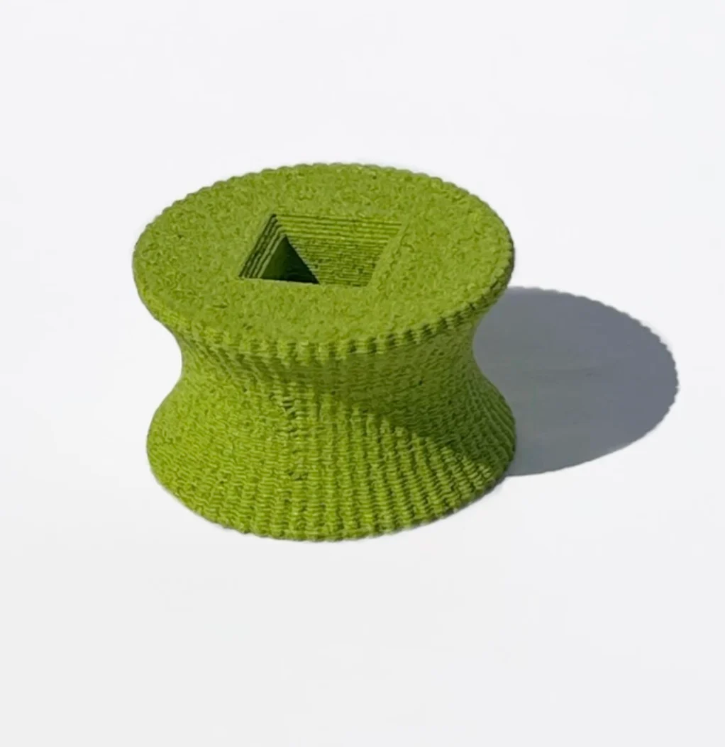 Rocchetto verde stampato in 3D con superficie materica e apertura quadrata su fondo bianco – Deep Surfaces a Palazzo Zorzi, Venezia, Italia, 2025 – allestimento espositivo