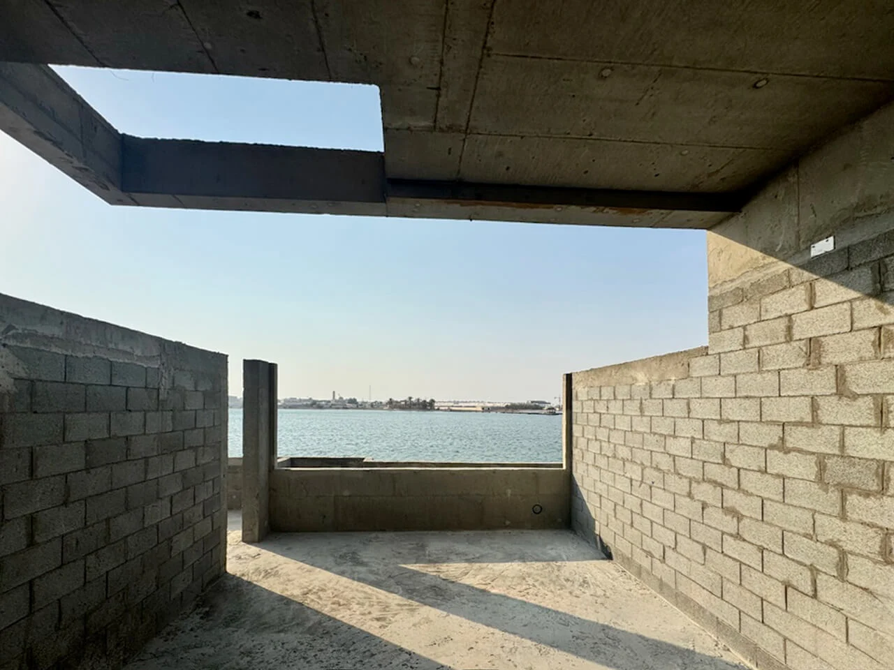 Stanza incompiuta in blocchi di cemento che inquadra la vista sul mare sotto un solaio di copertura aperto – Radic Residences, Jeddah, Arabia Saudita, 2025 – architettura, in costruzione