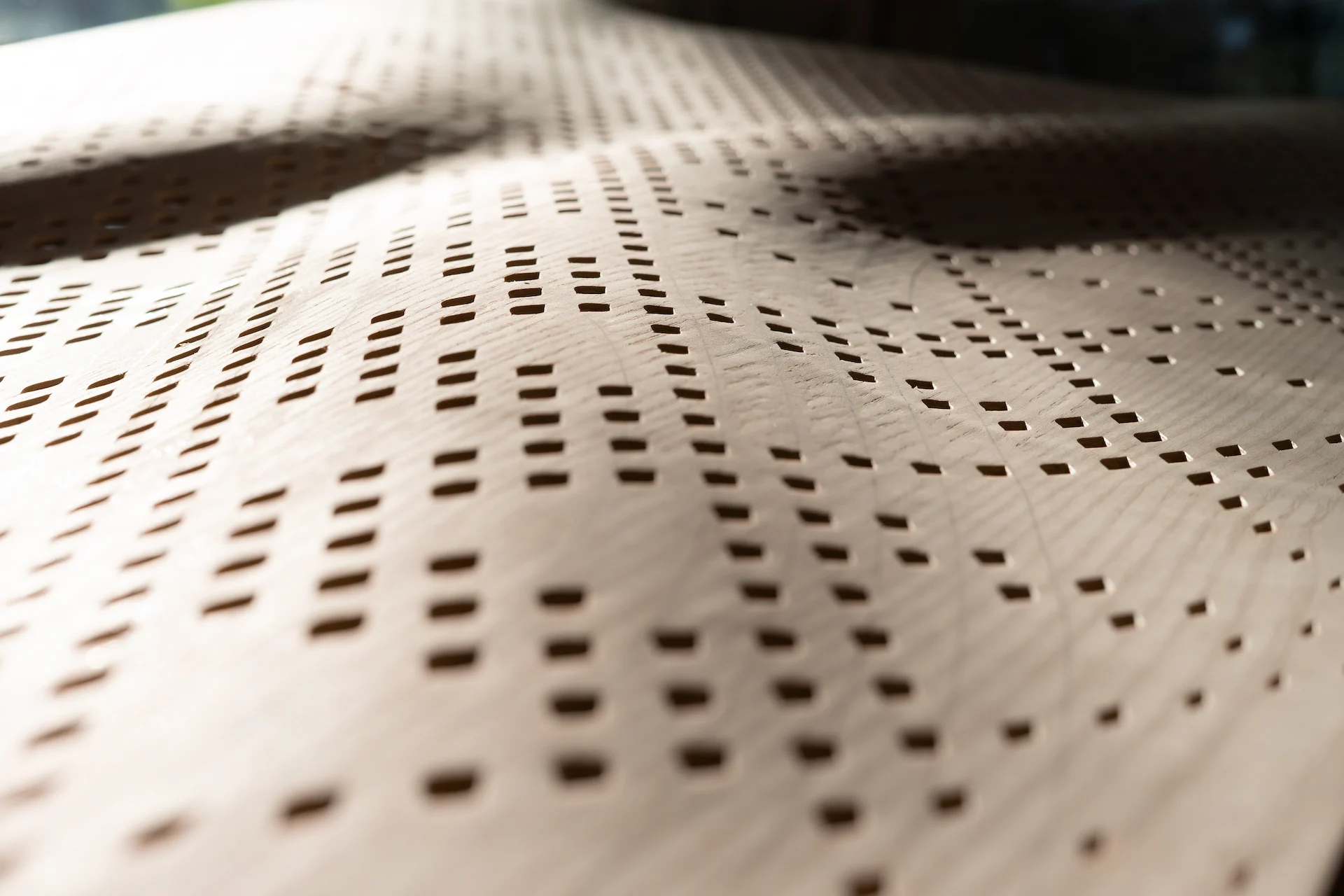 Dettaglio di un pannello curvo in legno traforato con file di piccoli fori rettangolari – Pannelli acustici Najdi per Strong by Form, 2025 – design di prodotto