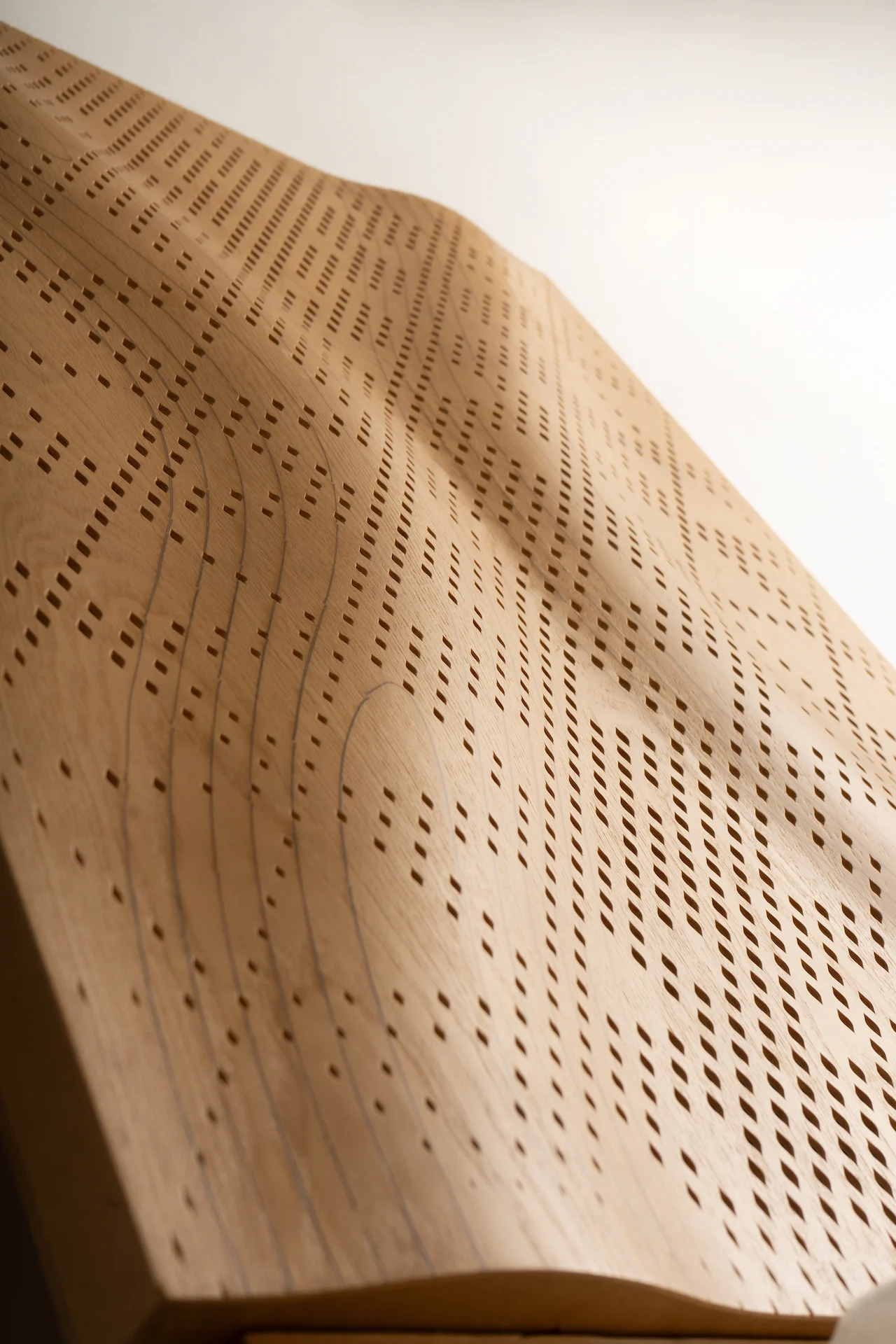 Dettaglio di scorcio di un pannello curvo in legno traforato con la venatura in vista – Pannelli acustici Najdi per Strong by Form, 2025 – design di prodotto