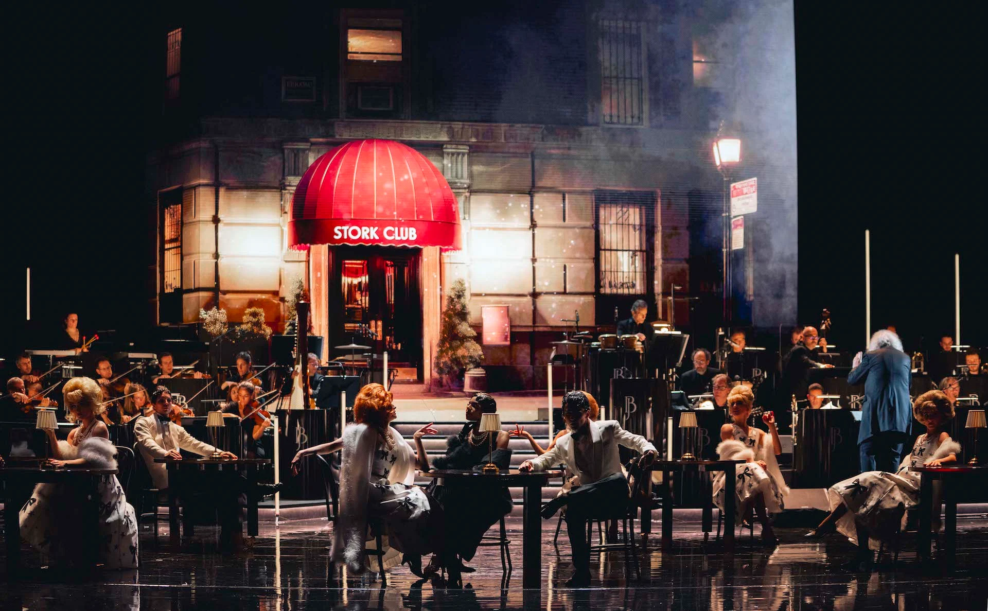 Scenografia di una strada notturna con la tenda rossa dello Stork Club, artisti seduti ai tavoli e l'orchestra nella foschia – Bonsoir Monte-Carlo, Monte Carlo, Principato di Monaco, 2025 – scenografia