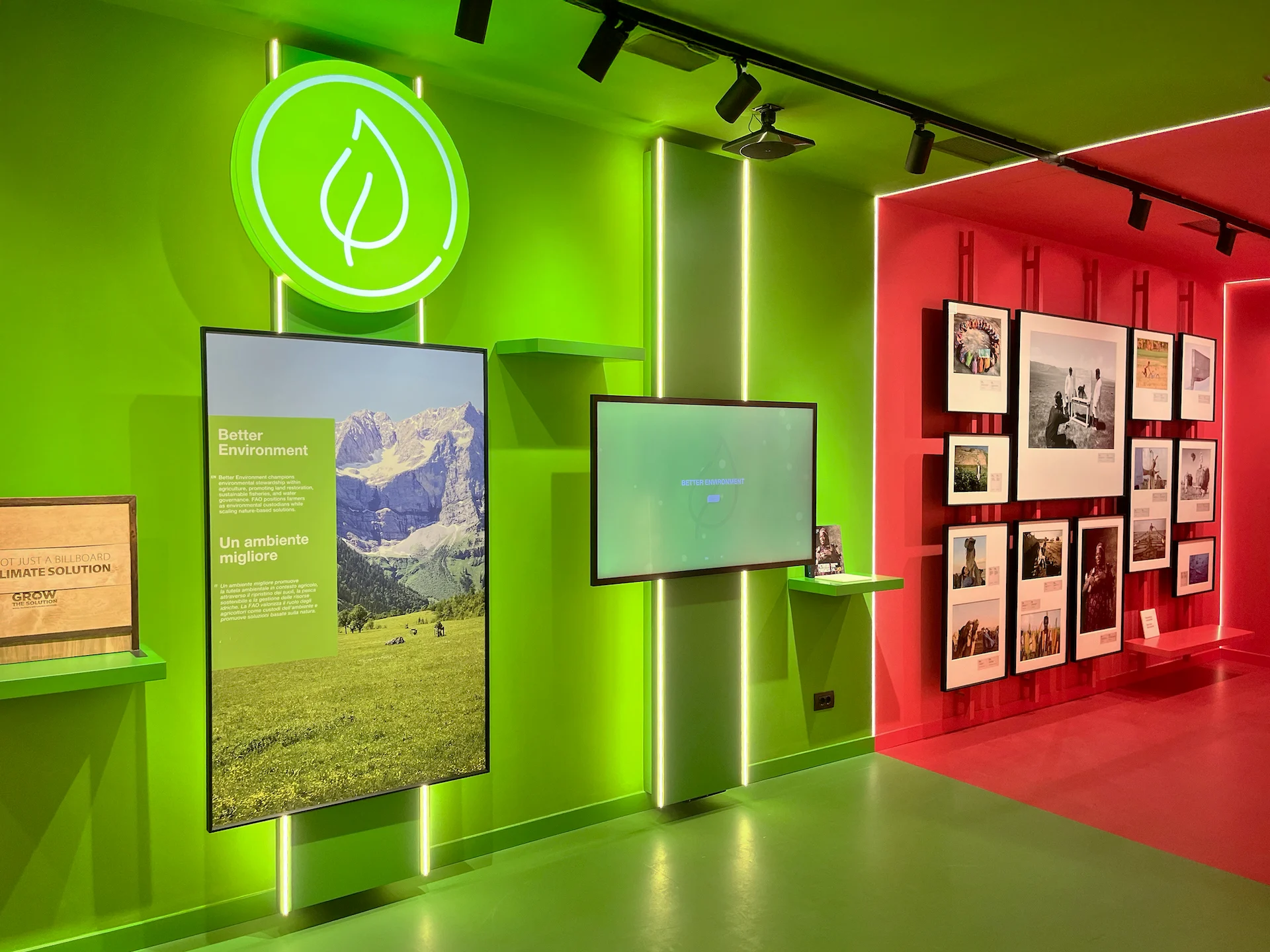Parete espositiva verde brillante con uno schermo che mostra un paesaggio, accanto a una sala rossa con fotografie incorniciate – FAO MuNe Museo dell'alimentazione e dell'agricoltura, Roma, Italia, 2025 – allestimento espositivo