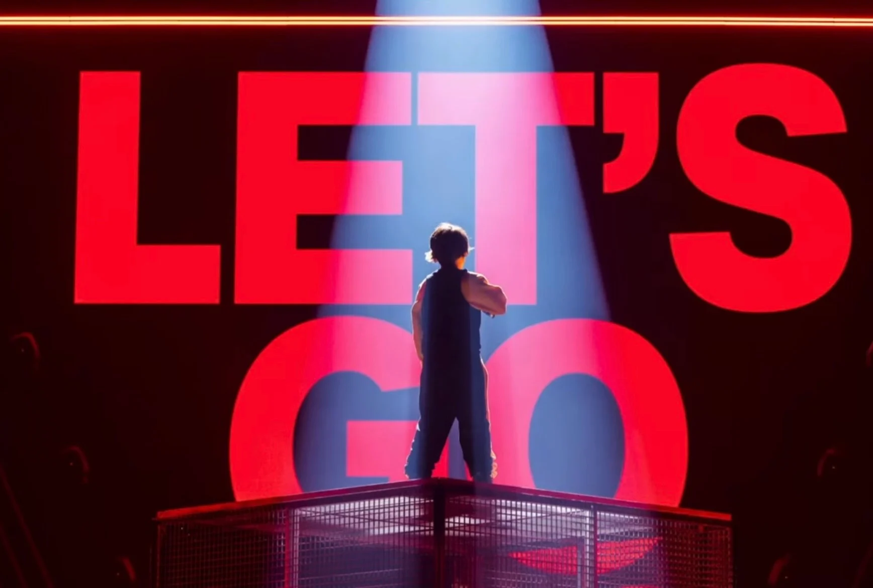 Cantante visto di spalle sulla pedana, davanti a gigantesche lettere LED rosse con la scritta LET'S GO – Leonardo Giovannangeli al Junior Eurovision 2025, Tbilisi, Georgia – scenografia per concerti