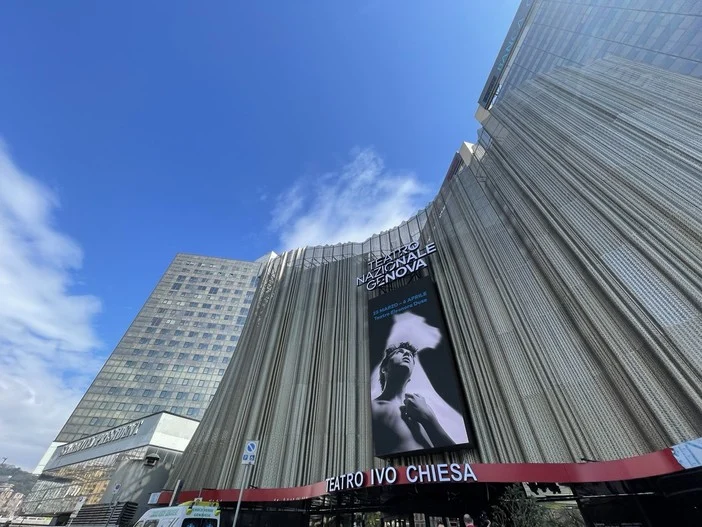 Facciata metallica plissettata del Teatro Nazionale Ivo Chiesa con un grande schermo verticale contro il cielo blu – Facciata del Teatro Nazionale Ivo Chiesa, Genova, Italia, 2025 – riqualificazione architettonica