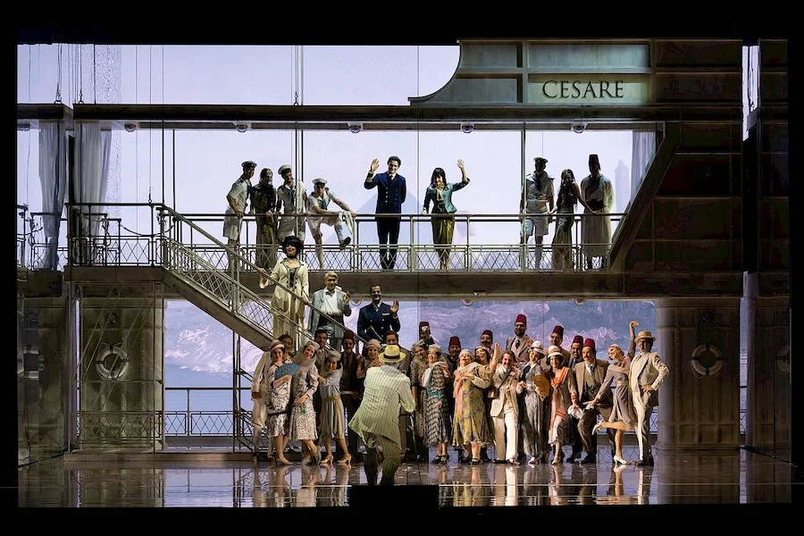 Coro e solisti su una scenografia a forma di nave su due livelli con una scala e la scritta CESARE in alto – Giulio Cesare in Egitto all'Opéra de Monte-Carlo, Principato di Monaco, 2025 – scenografia d'opera