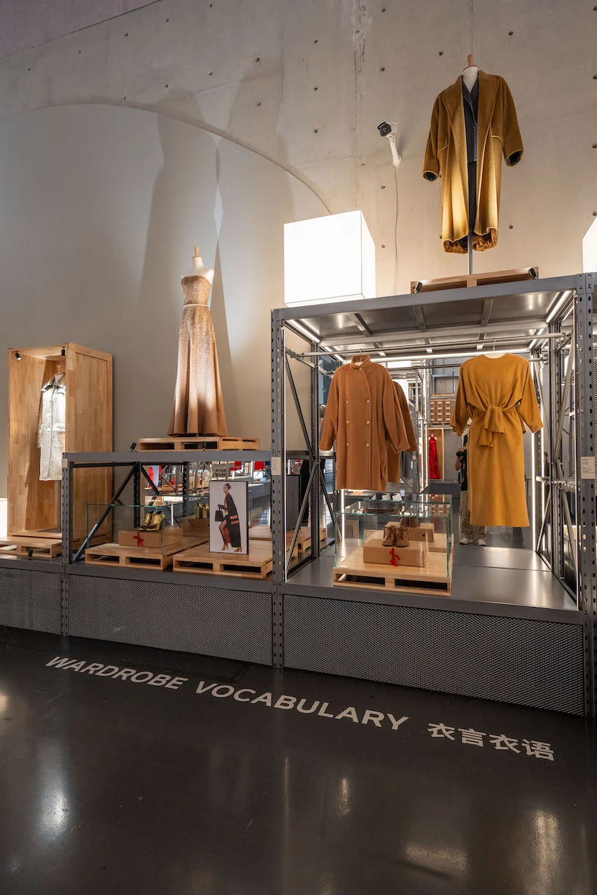 Sezione Wardrobe Vocabulary: capi cammello e senape e un abito da sera esposti su scaffalature metalliche – Max Mara The Max! al Long Museum, Shanghai, Cina, 2026 – allestimento espositivo