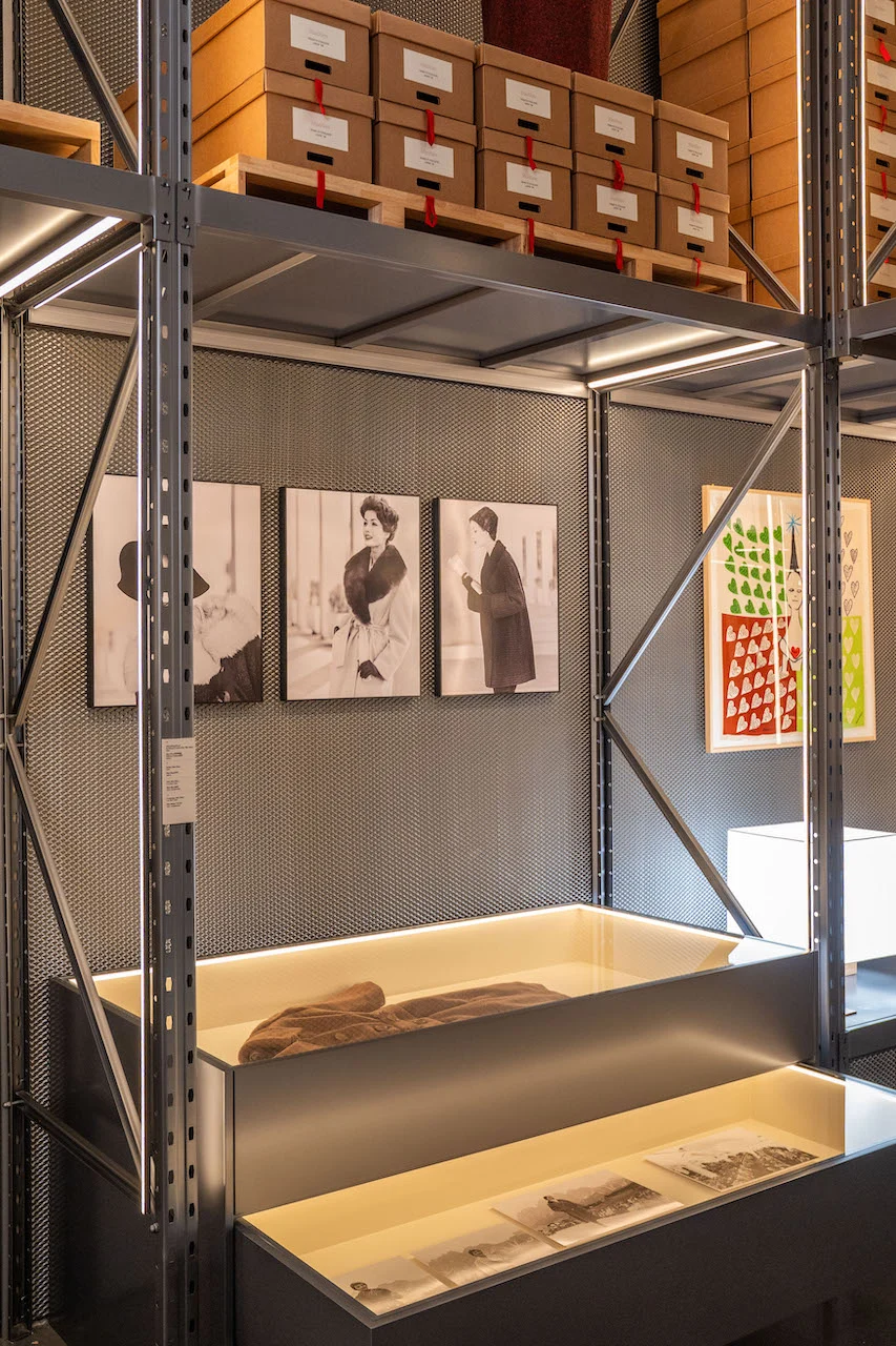 Scaffalatura metallica con scatole d'archivio, fotografie di moda in bianco e nero e vetrine illuminate sotto – Max Mara The Max! al Long Museum, Shanghai, Cina, 2026 – allestimento espositivo