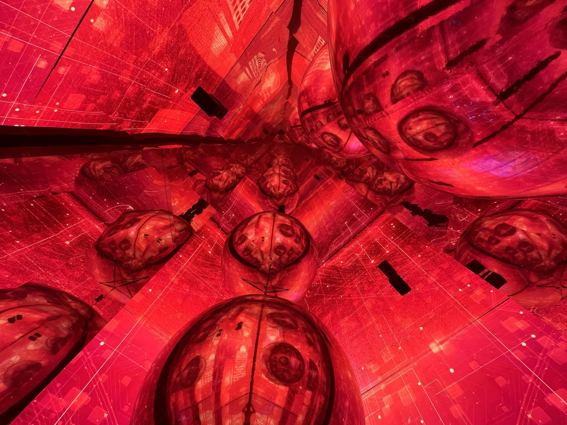 Soffitto a specchio che riflette sfere illuminate di rosso e schermi LED, creando un effetto caleidoscopico infinito – Mastercard Innovation Forum 2023, Milano, Italia – progettazione di eventi
